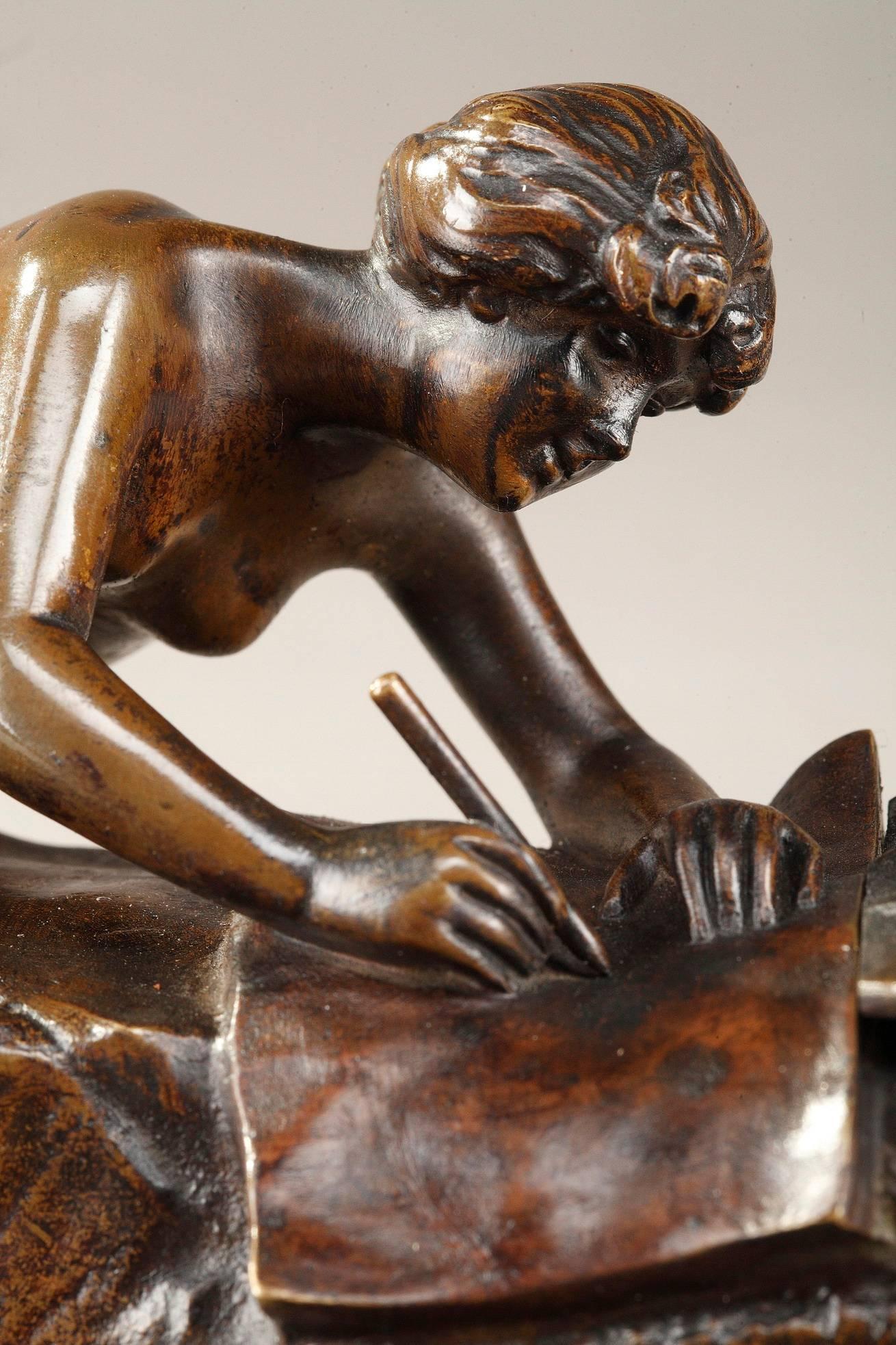 Small patinated bronze sculpture forming an inkwell and representing a young nymph writing, lengthened on a bed of reeds and plant motifs. By Karl (Charles) Korschann (Czech, 1872-1943). The buckets for ink are hidden under two large leaves. The