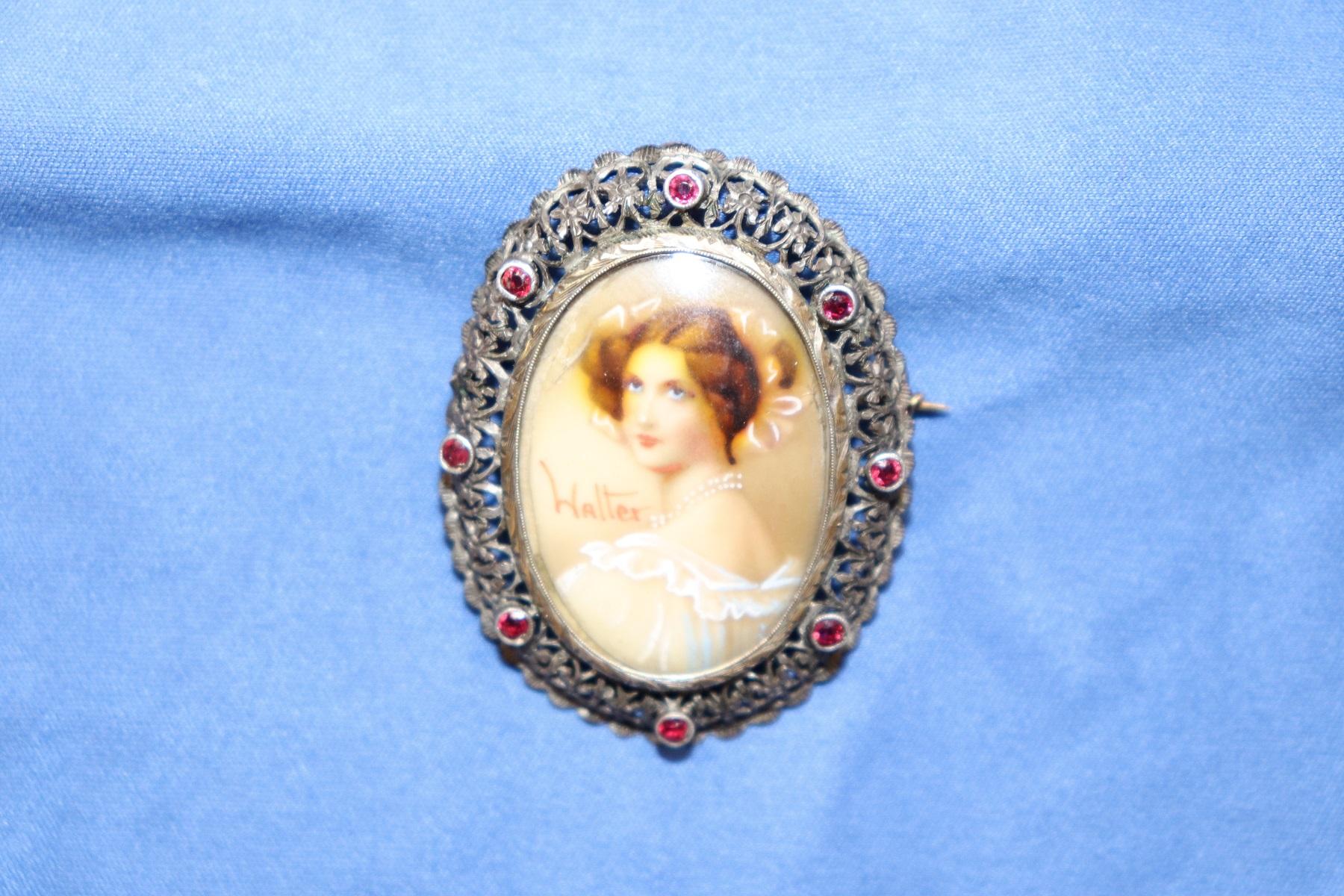 Elegant Art Nouveau oval brooch with gold and silver filigree embellished with eight red ribbons. In the centre a portrait of a young miniature woman painted by hand with a brush tip. Extremely refined painting signed by the artist Walter.
Weight