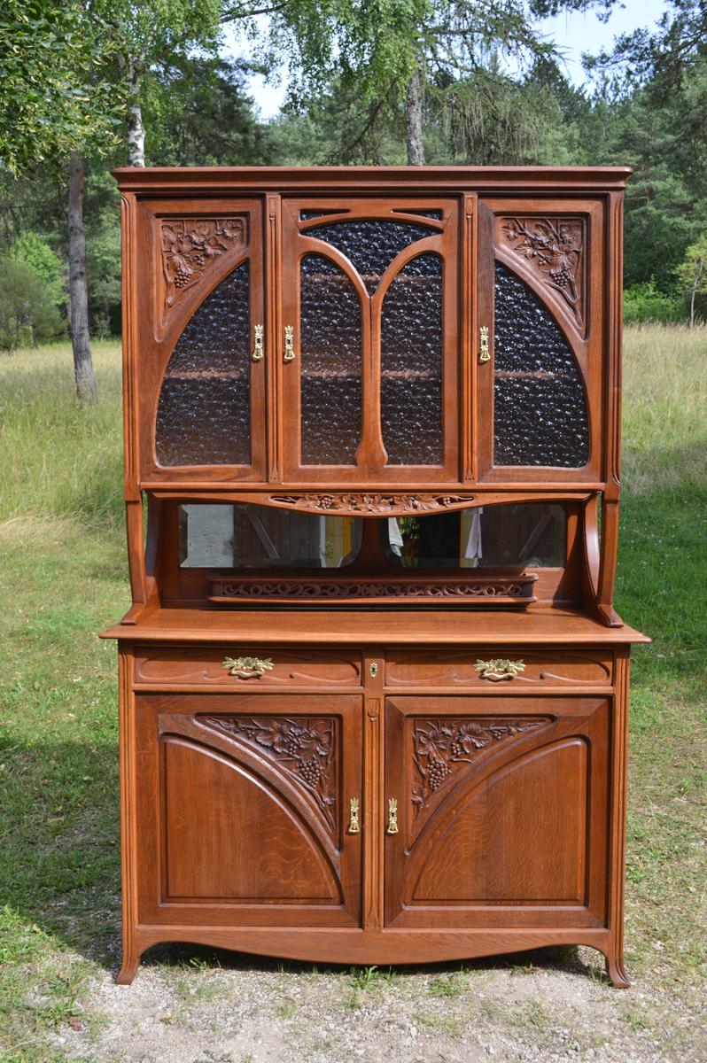 This two parts Art Nouveau buffet is made of solid chestnut with carved vine branch details to the front.

Made by Edouard Diot.

In the upper part, the cabinet features two beveled mirrors and a carved openwork wooden shelf. Above, a large