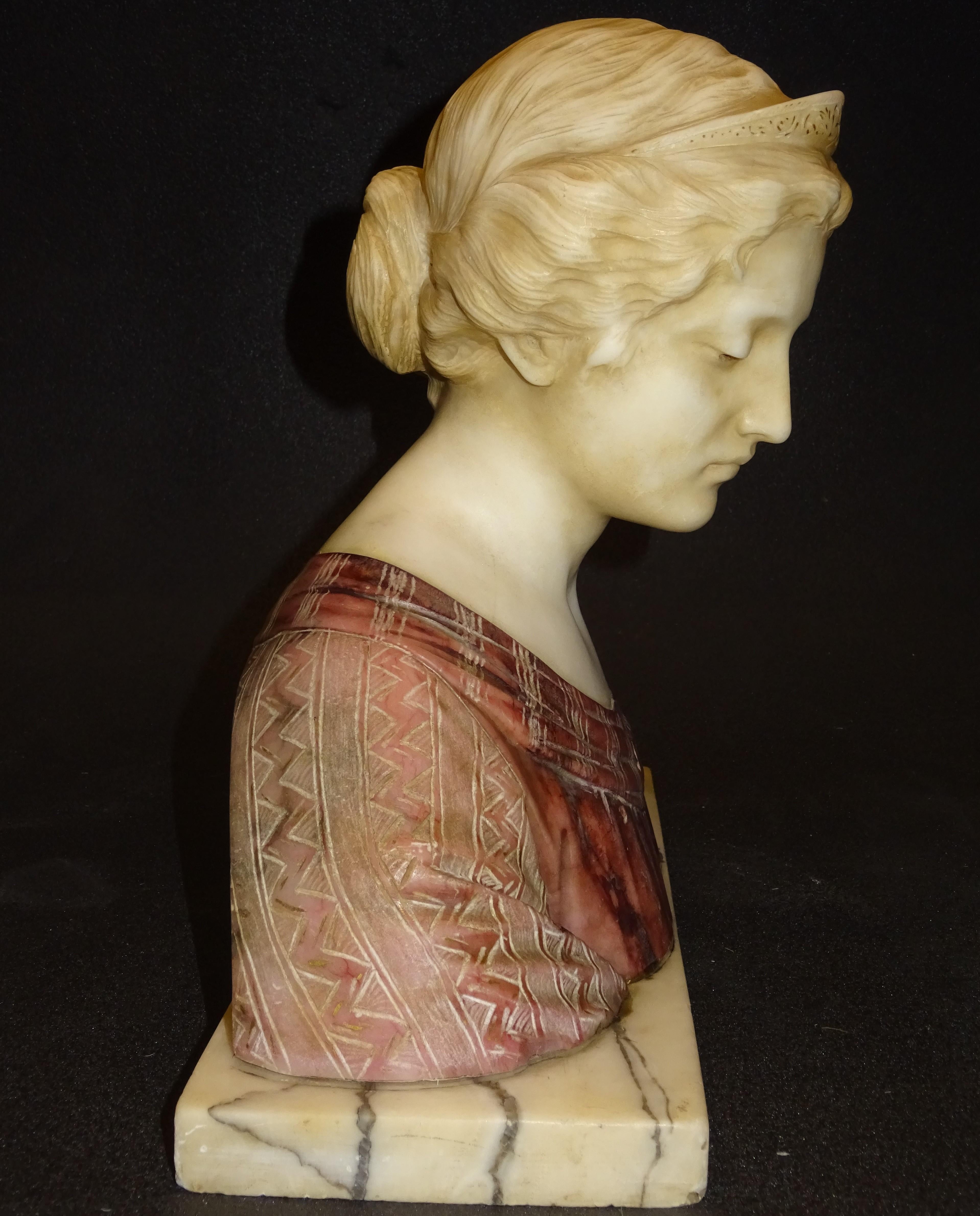 Magnificent bust in made combining two types of alabaster, one that shades broken white for the face and base of the piece and another with a reddish finish to contrast the dress that wears the figure. It appreciates the great elegance in the forms
