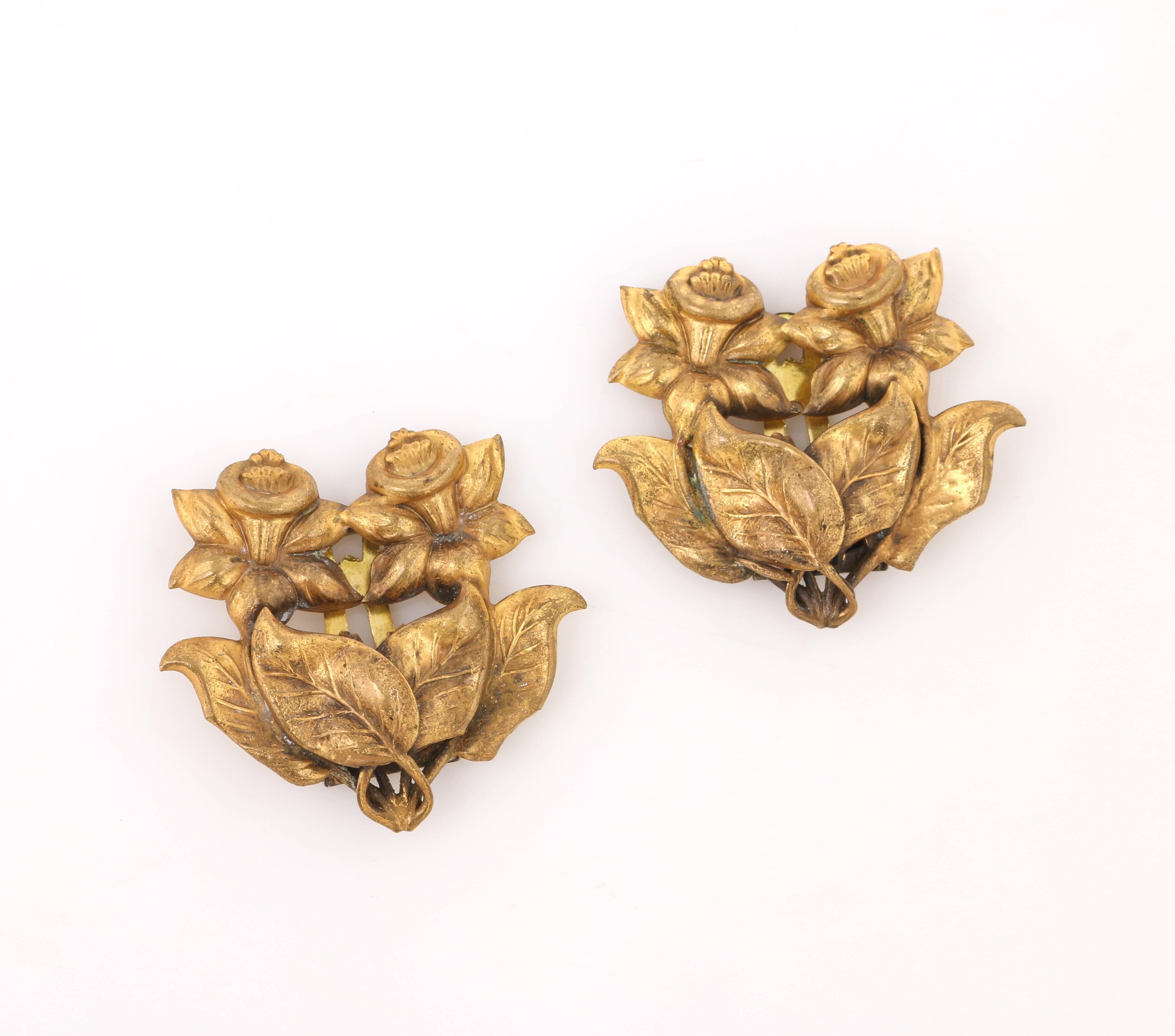 Vintage Art Nouveau c.1930's two piece brass daffodil motif dress / fur clips set. Brass-toned pressed metal interlocking daffodil motif. Hinged brass-toned metal clip at back. Both pieces are unmarked. Measurements:

Length: 1.75