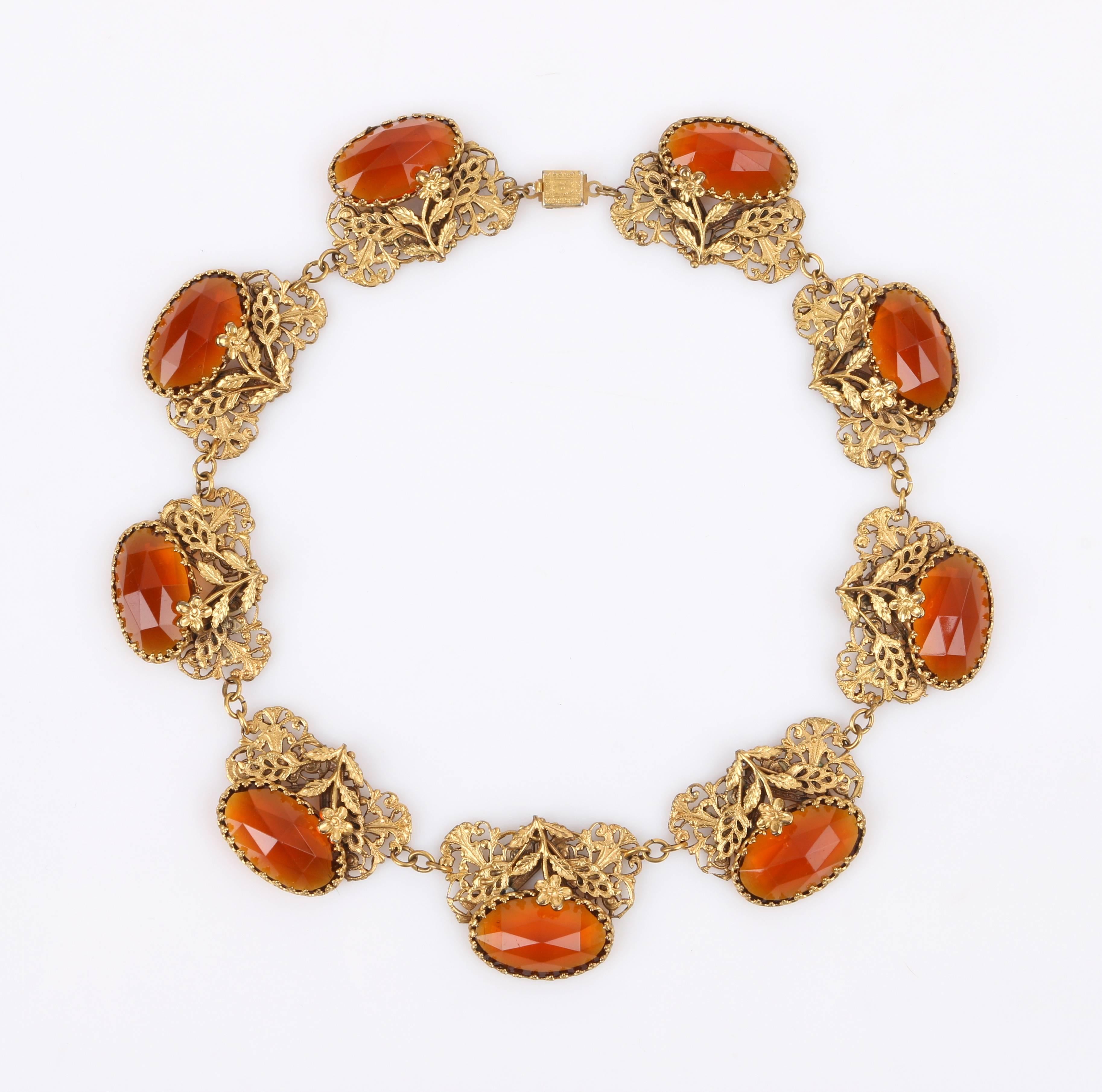 Vintage Art Nouveau c.1930's floral filigree brass and amber Czech glass choker necklace. Nine faceted oval amber czech glass gems prong set into a brass-toned metal open work filigree setting with single flower overlay. Each setting is linked