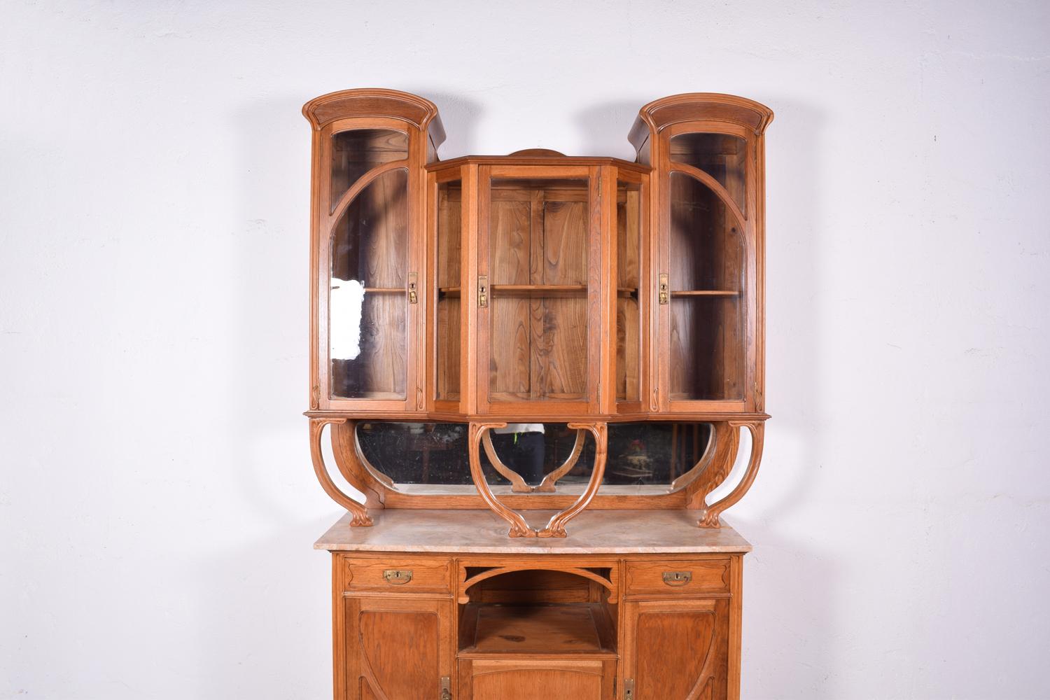 Oak cabinet, similar model in Gustave Serrurier-Bovy. On the front upper part has three glass doors with the original and antique glass, and in the lower part has three doors, two drawers and an open space. The handles and hinges are in hammered