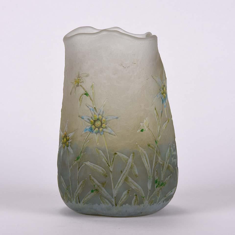 Merveilleux vase en verre camée décoré de fleurs d'Edelweiss complexes sur fond de paysage givré, présentant des détails très fins et des couleurs enchanteresses. Signé sur la base Daum Nancy et avec la croix de Lorrain.

Daum Frères (français,