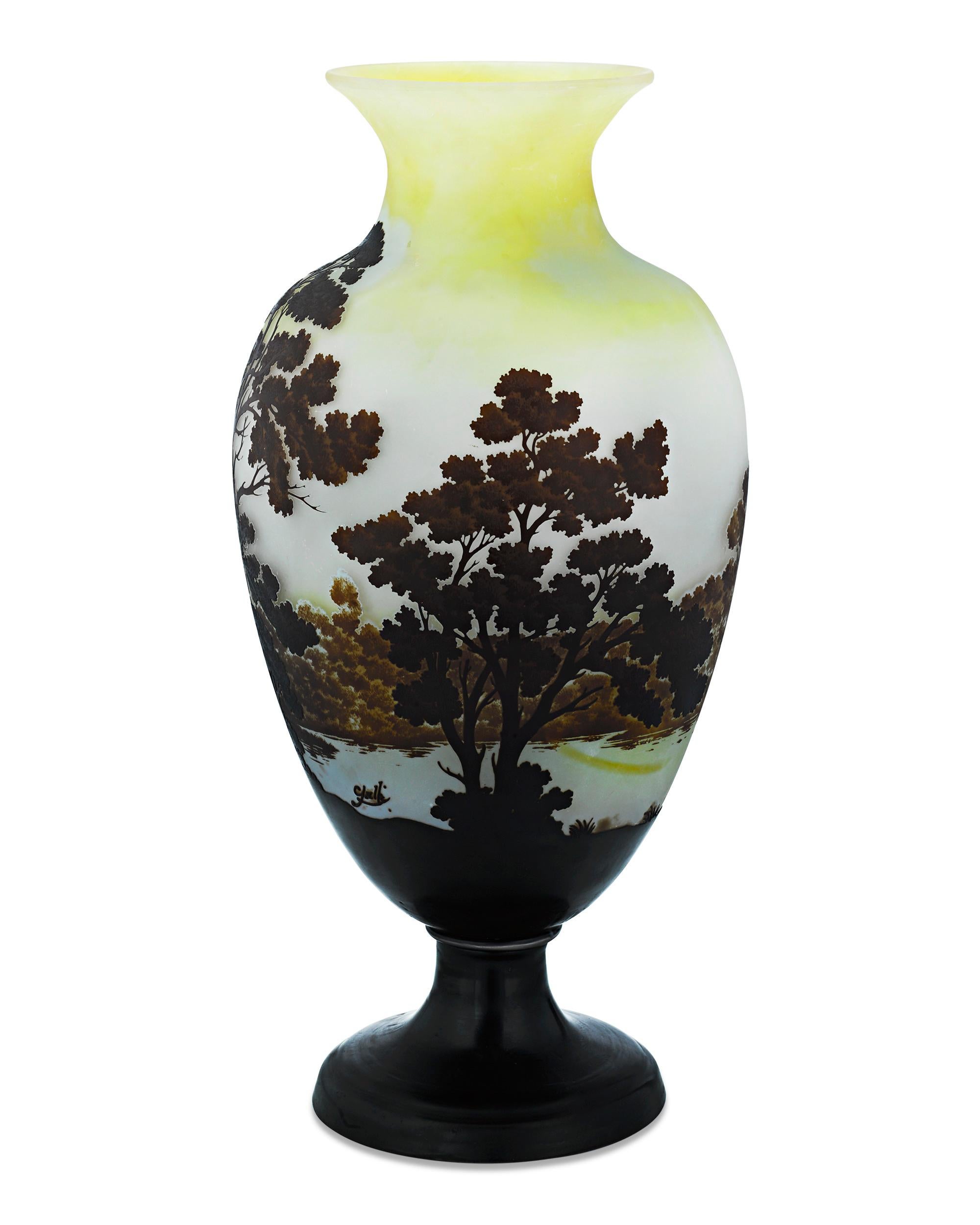 This exceptional cameo art glass vase is the work of the famed Art Nouveau master Emile Gallé. The artist's love of nature is evident in this naturalistic wooded landscape scene set in a sundown yellow backdrop. The Gallé cameo signature is set