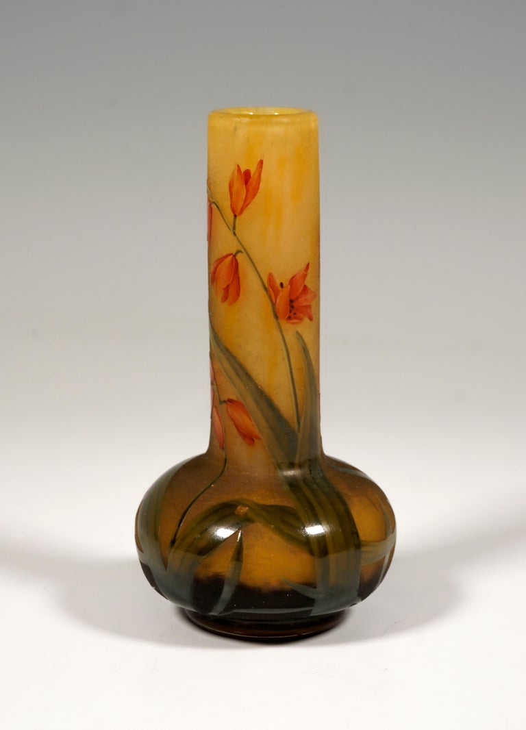 Small long neck vase with bulbous base and round stand, colorless glass with flaky white and yellow, in the stand area with dark brown powder melts, with etched Montbretian decor painted in colored enamel, satined surface in the background, relief