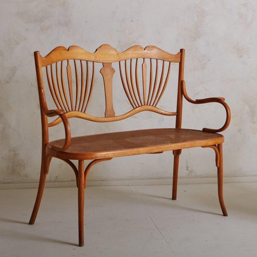 Ein Fischel zugeschriebener Vintage-Liegesessel mit einem geschnitzten Holzrahmen und einer aufwändig verzierten Rückenlehne. Dieser Sessel hat einen Sitz aus Schilfrohr und geschwungene Bugholzarme. Sie ist im Fischel-Katalog Nr. 150 dokumentiert.