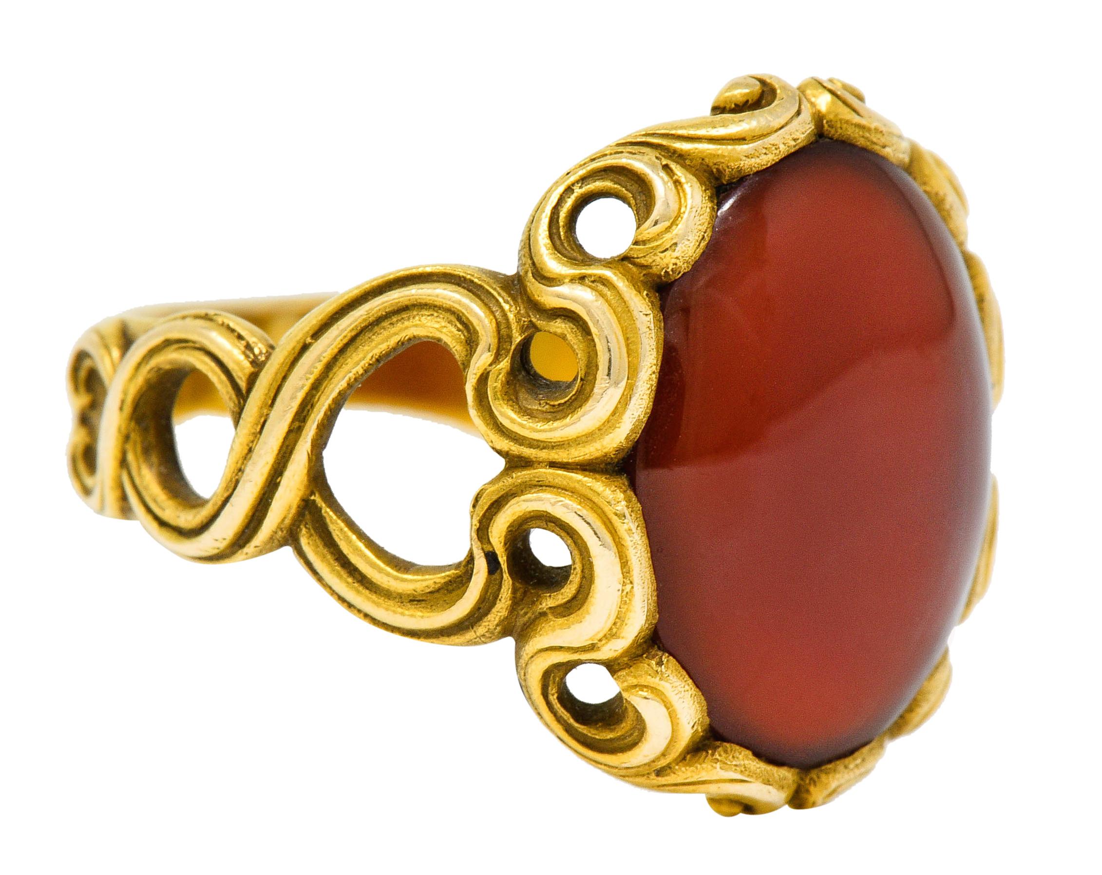 Centering an oval cabochon of carnelian measuring approximately 15.5 x 11.5 mm

Translucent with uniform brownish-red color

With a scrolled whiplash surround and winding whiplash shoulders

Tested as 14 karat gold

Circa: 1905

Ring Size: 8 3/4 &