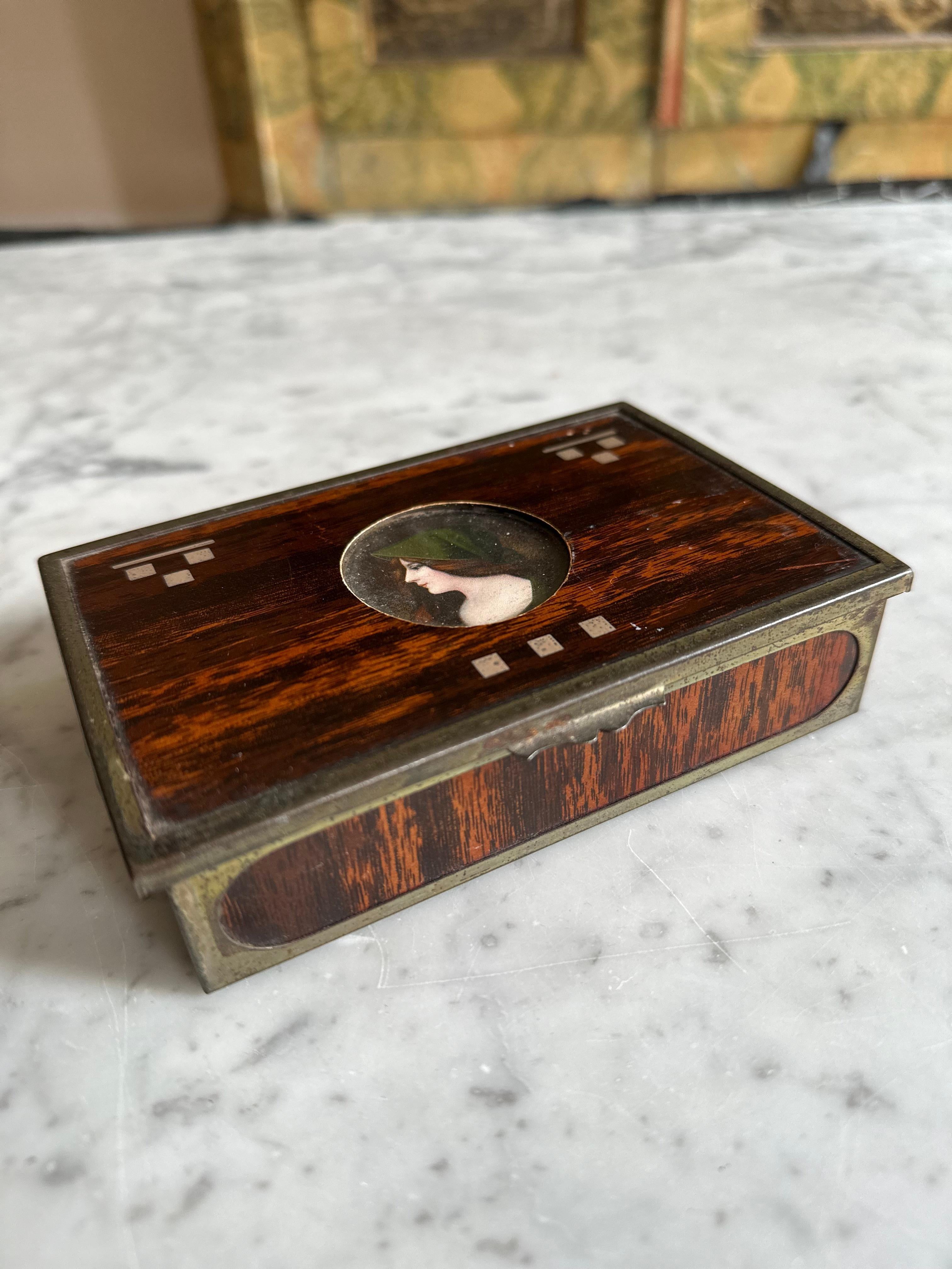 Wir stellen Ihnen unsere exquisite Small Rectangular Box vor, ein wunderschönes Relikt aus der Zeit um die Jahrhundertwende, das eine faszinierende Mischung aus verschiedenen künstlerischen Stilen darstellt. Diese charmante Schachtel ist ein Zeugnis