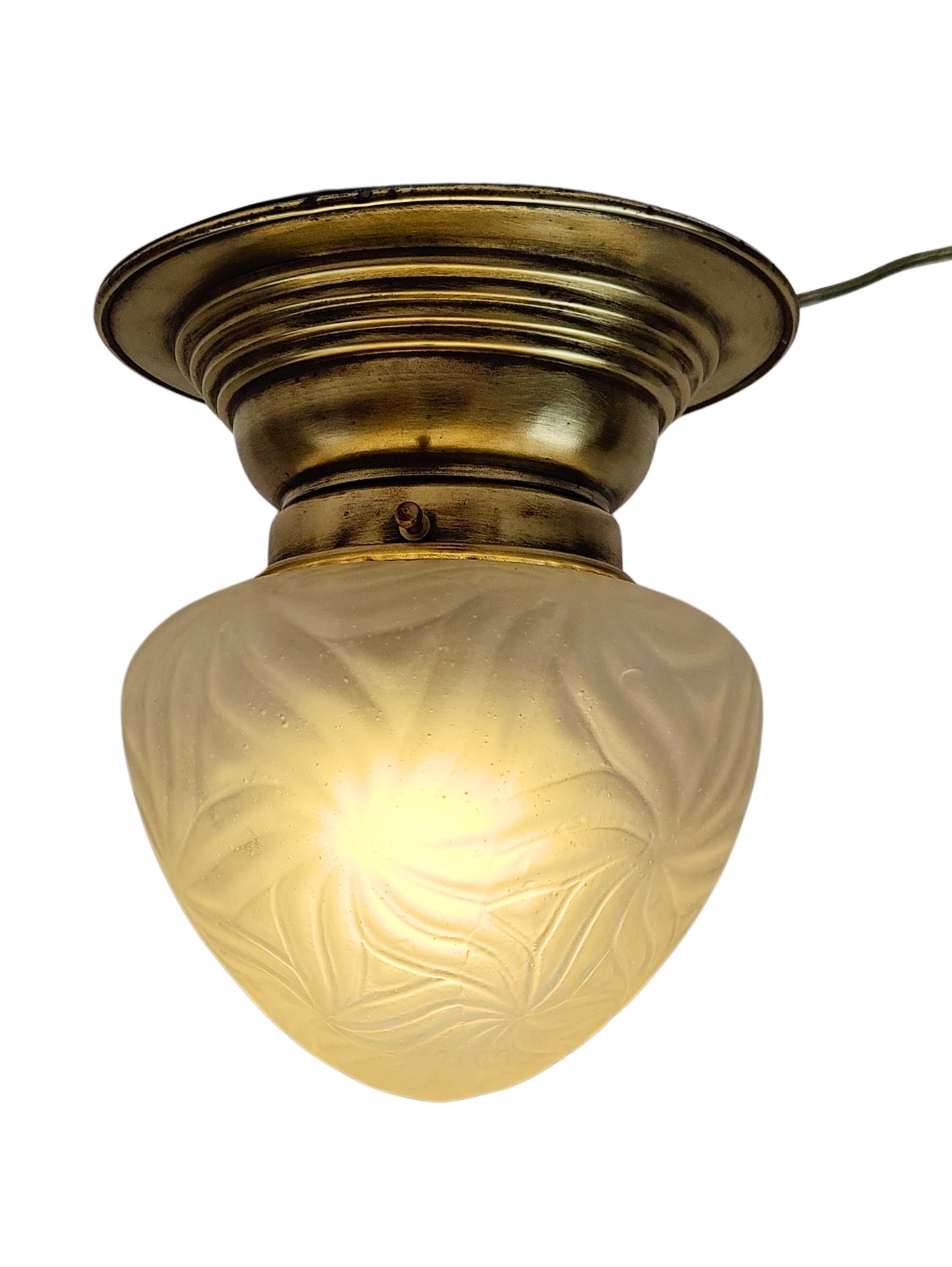 This authentic Art Nouveau ceiling light, crafted in Germany around 1910, features a beautifully aged brass fixture and a delicately etched satin glass shade. The floral pattern typical of the period lends an organic, soft elegance to the piece,