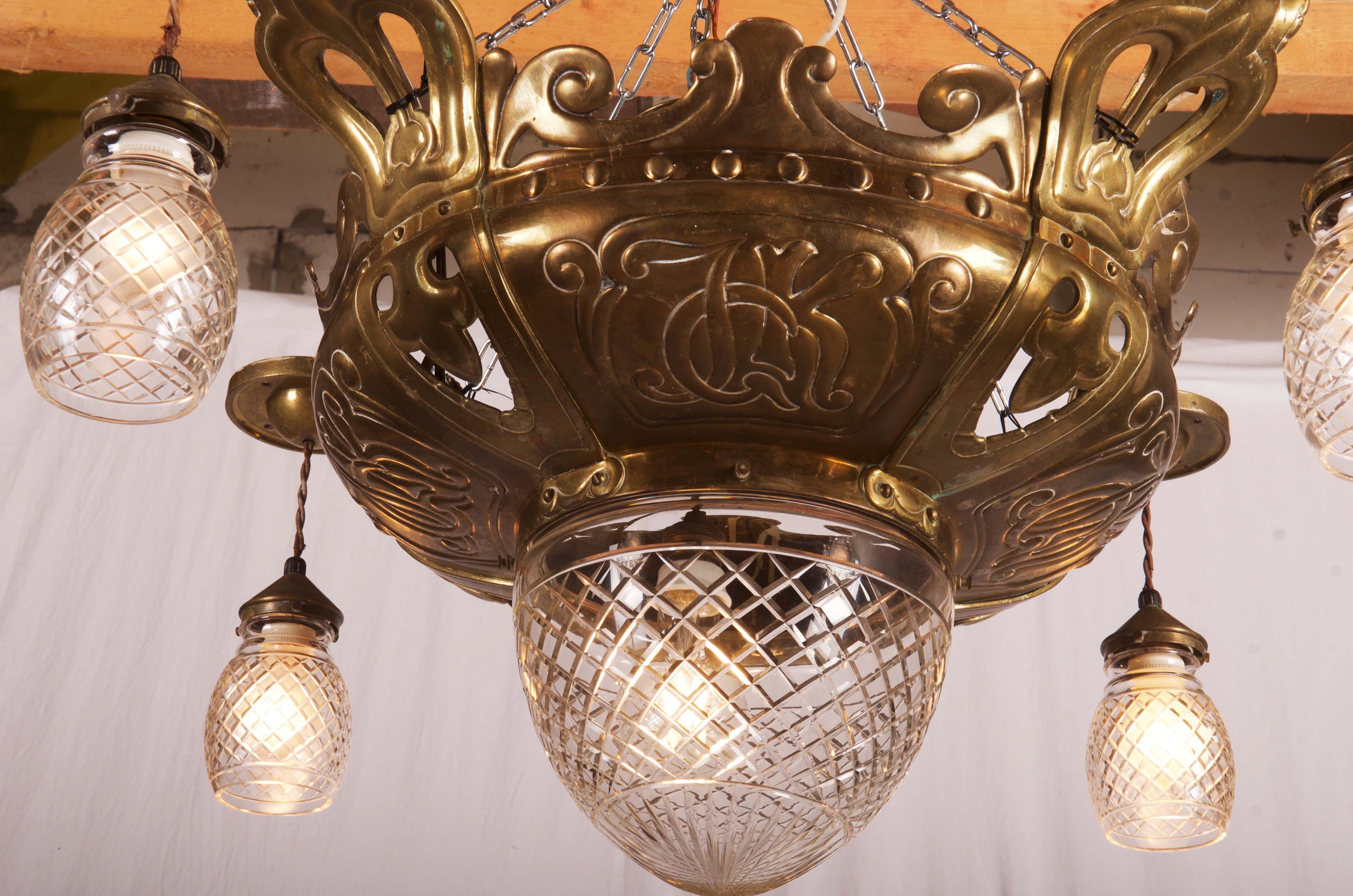 Brass crown decorated with organic ornamentation and monograms fitted with five E27 bulb and clear glass shades and bowl. Designed 1911 by Rudolf Frimodt Clausen for 