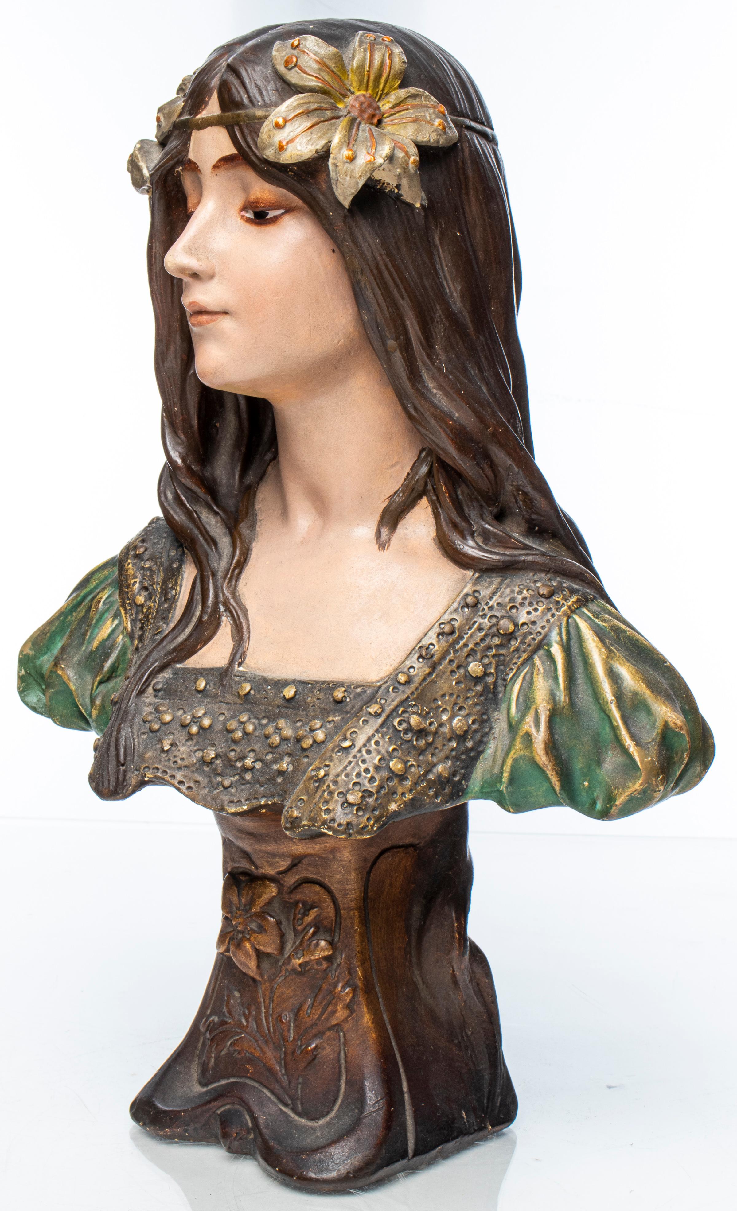 Art Nouveau ceramic portrait bust of a maiden, depicted with long flowing hair and floral wreath, stylized socle base with relief flowers. Measures: 15.5