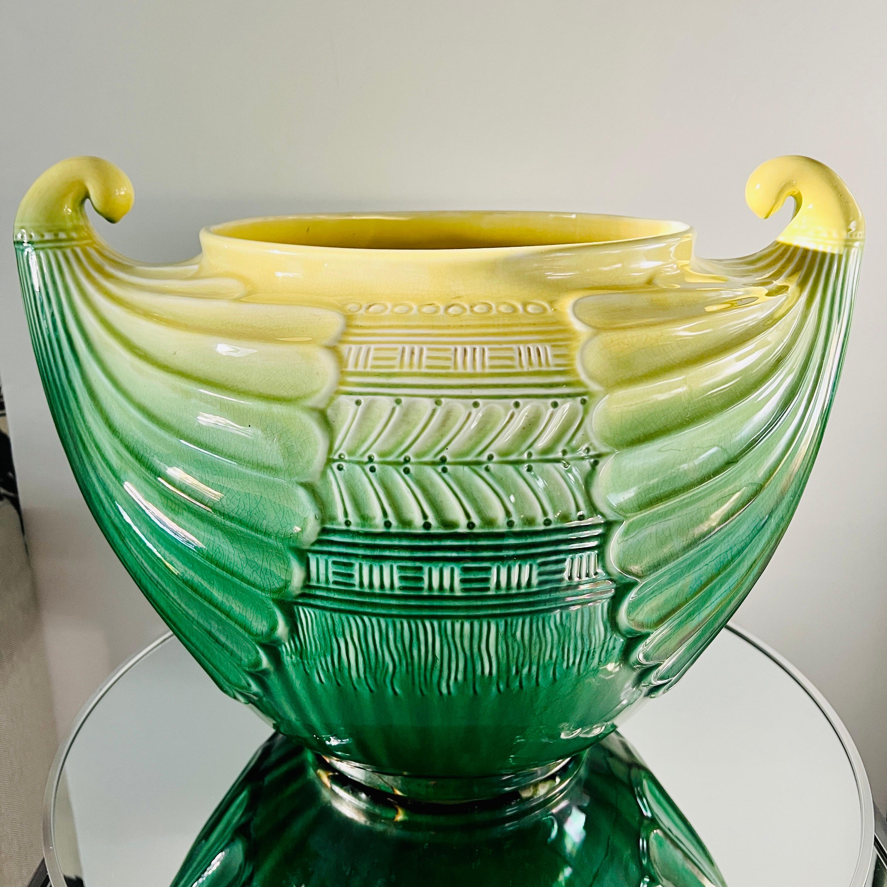 Large antique cachepot in green and yellow glazed terracotta by Christopher Dresser for SCI Laveno, Italy.  The urn features highly stylized fluted accents and scrolled handles, incorporating elements of both Art Nouveau and Art Deco designs. 