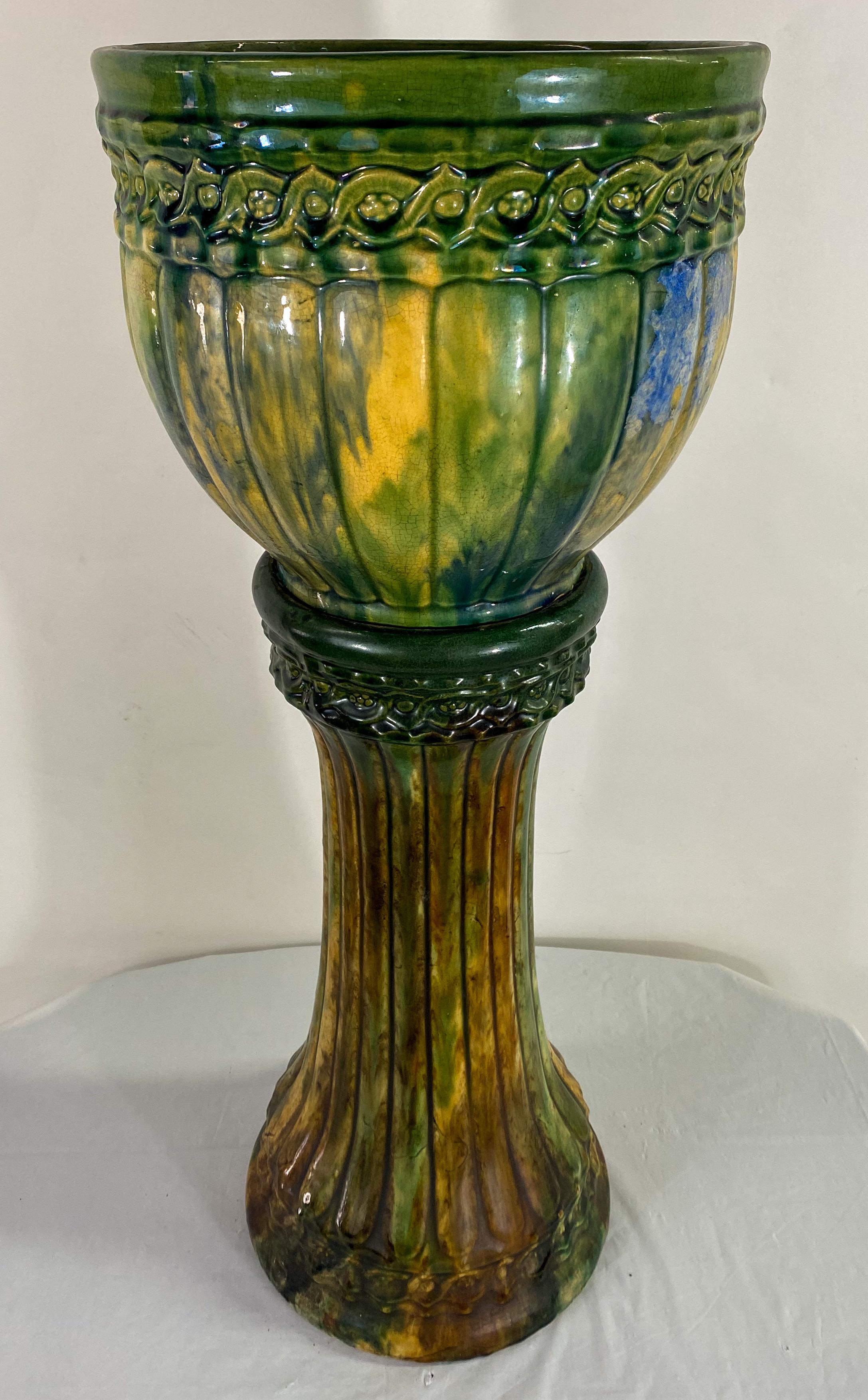 A beautiful Art Nouveau ceramic Majolica planter or jardiniere. The planter is standing on a beautiful pedestal both having exquisite ribbed squash design and featuring a vibrant green color with shades of yellow. 
The two-part jardiniere is