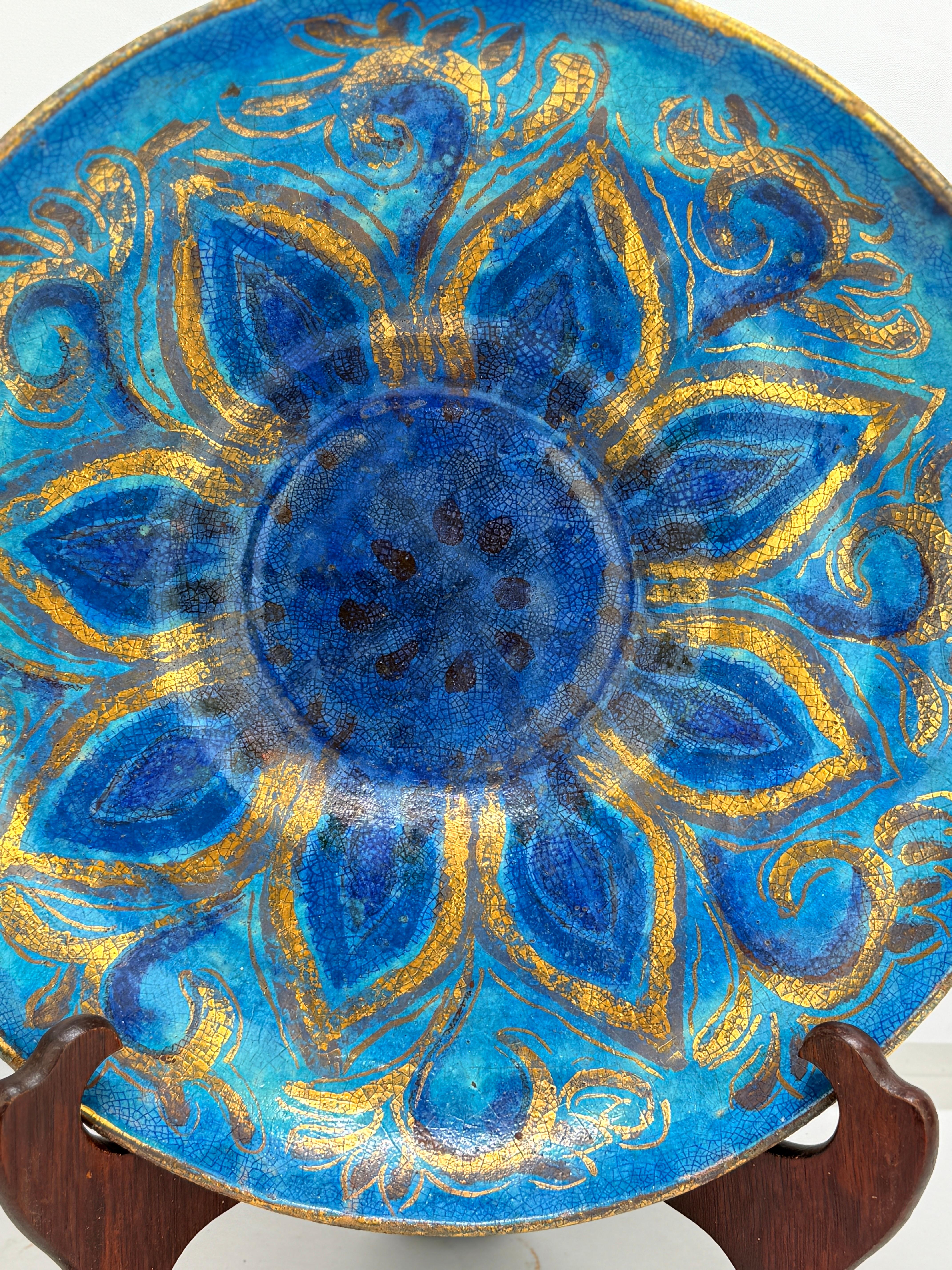 This striking hand-painted ceramic charger by Edith Cockcroft (1872–1962) is a stunning example of early 20th-century American art pottery. Measuring 14.75 inches in diameter, the plate features a radiant cobalt blue glaze adorned with an intricate