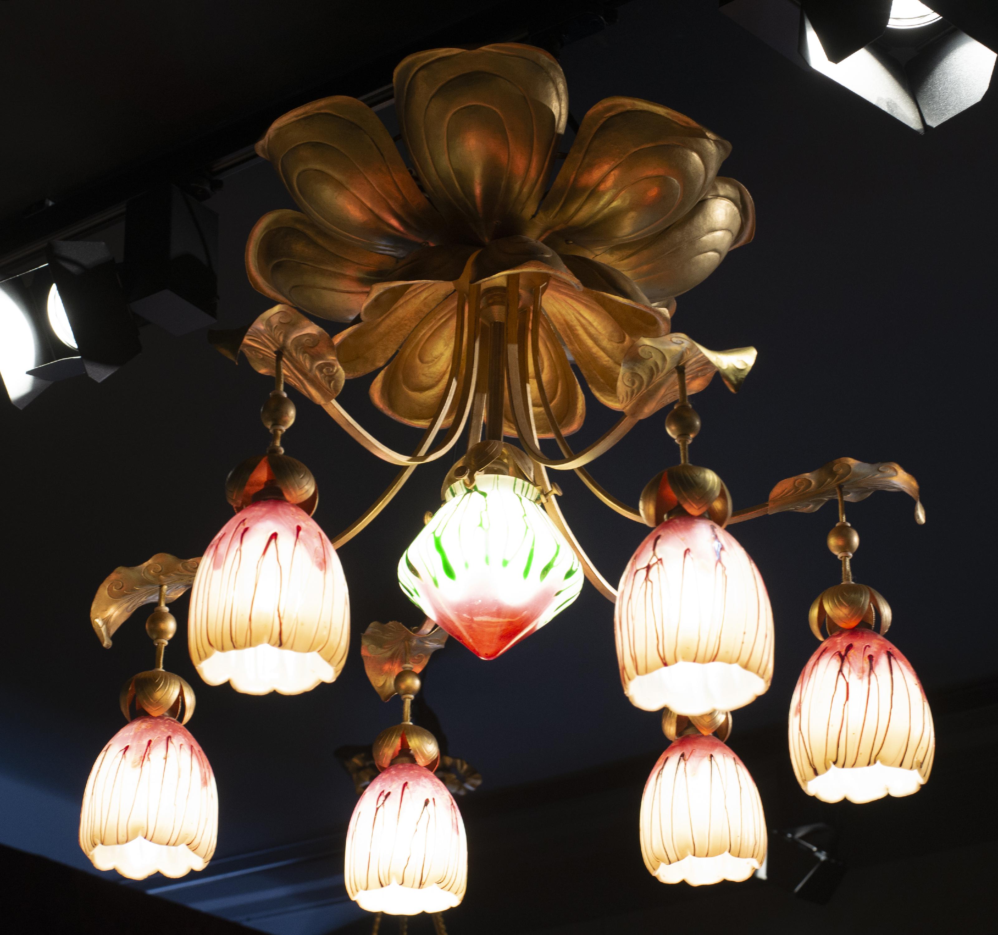 Art Nouveau style chandelier with seven lights, in patinated brass and glass paste tulips.