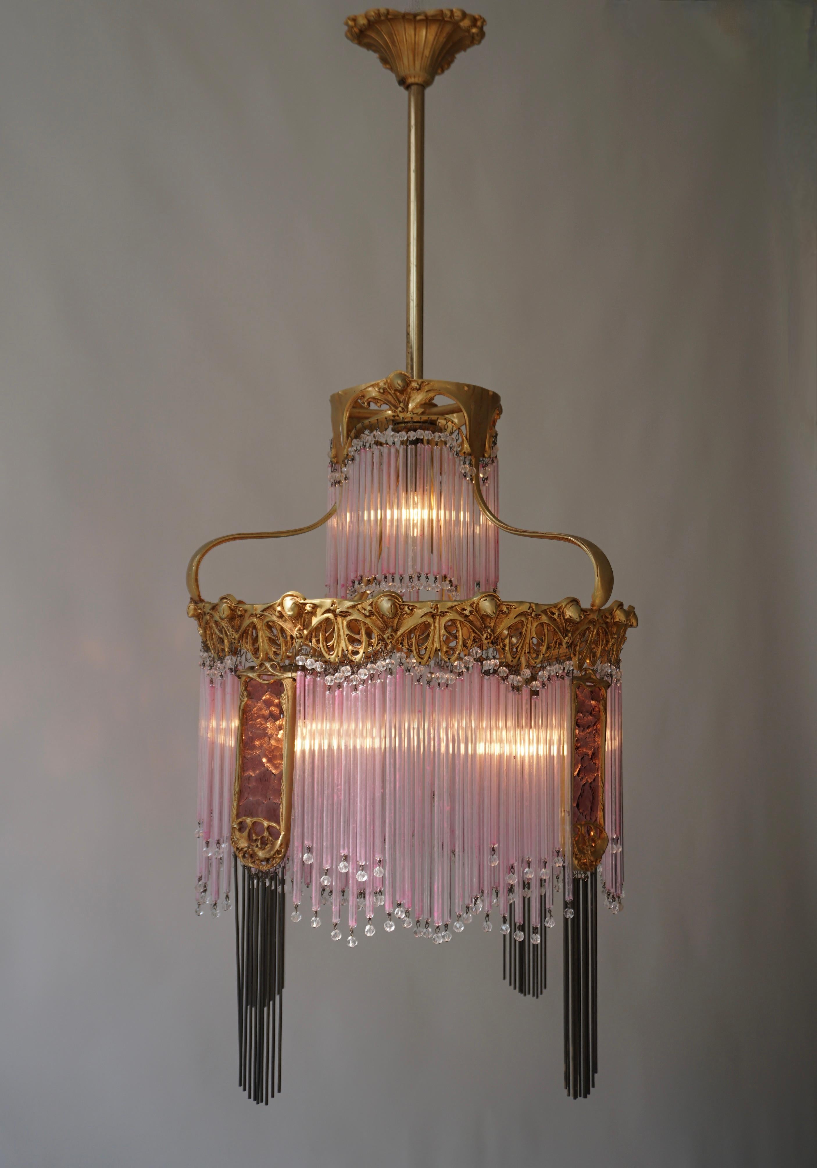 A spectacular and elegant chandelier made of hollow glass rods by Hector Guimard, France 1900. Art-Nouveau, Art-Déco, Néo-Classique, Shabby-Chic; structure or crown in golden bronze, fluid lines and motifs, tassels forming rods and glass perles