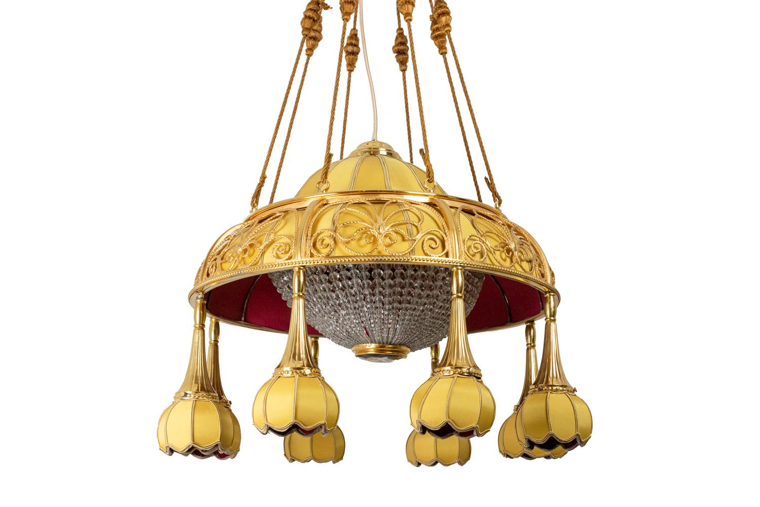 Art Nouveau chandelier composed by a bell shape ribbed lampshade covered by a yellow red fabric. It covered a half-sphere in transparent glass composed by beads swags and centered by a faceted cabochon. It is adorned by a gilt bronze openwork crown