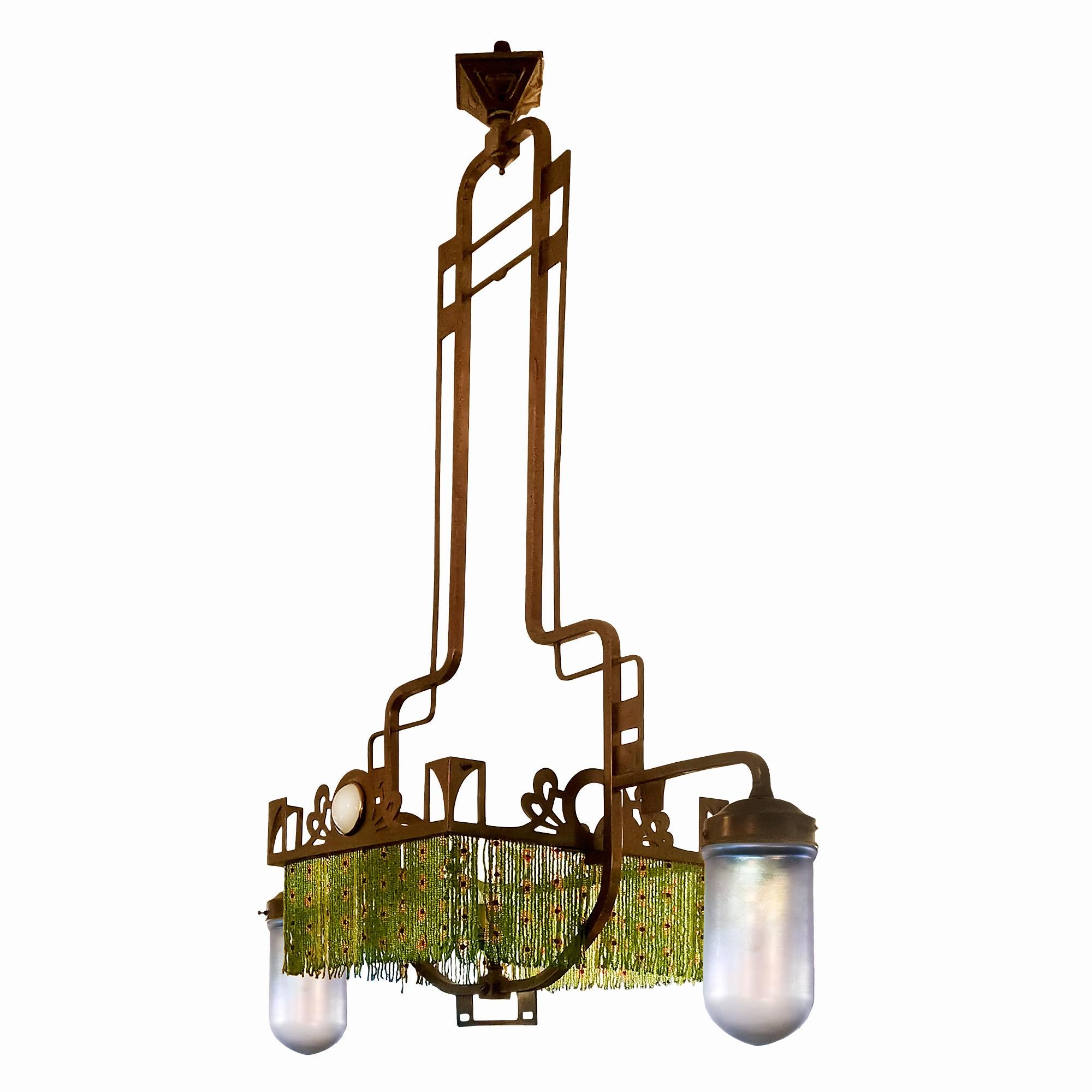Art Nouveau chandelier in polished brass formerly powered by gas, three points of light, two of which are covered by opalescent glass tulips matching the two thick glass pellets. The row of coloured glass beads hide the third bulb.

Italy, circa