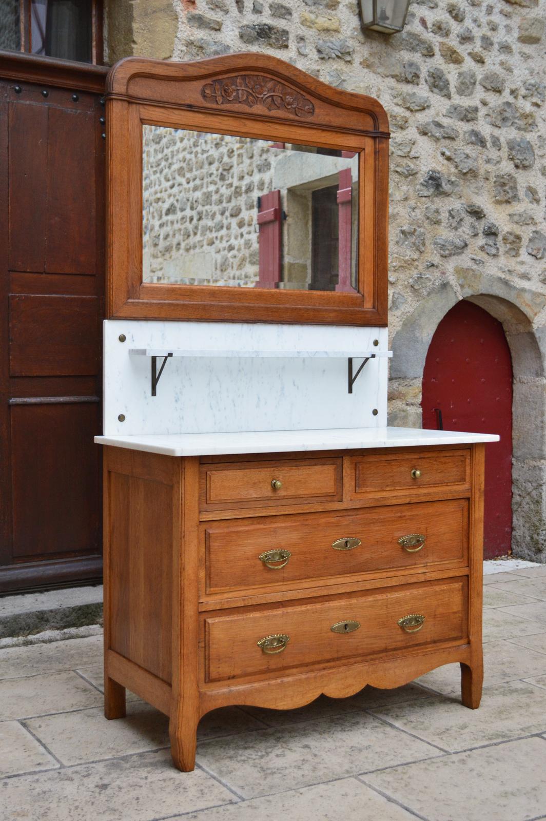 Pretty chest of drawers / commode / dressing or vanity table in solid oak with 4 drawers and a white marble top, surmounted by a small marble shelf and a beveled mirror beautifully carved with flowers.

Art Nouveau, France, circa 1910.

In very