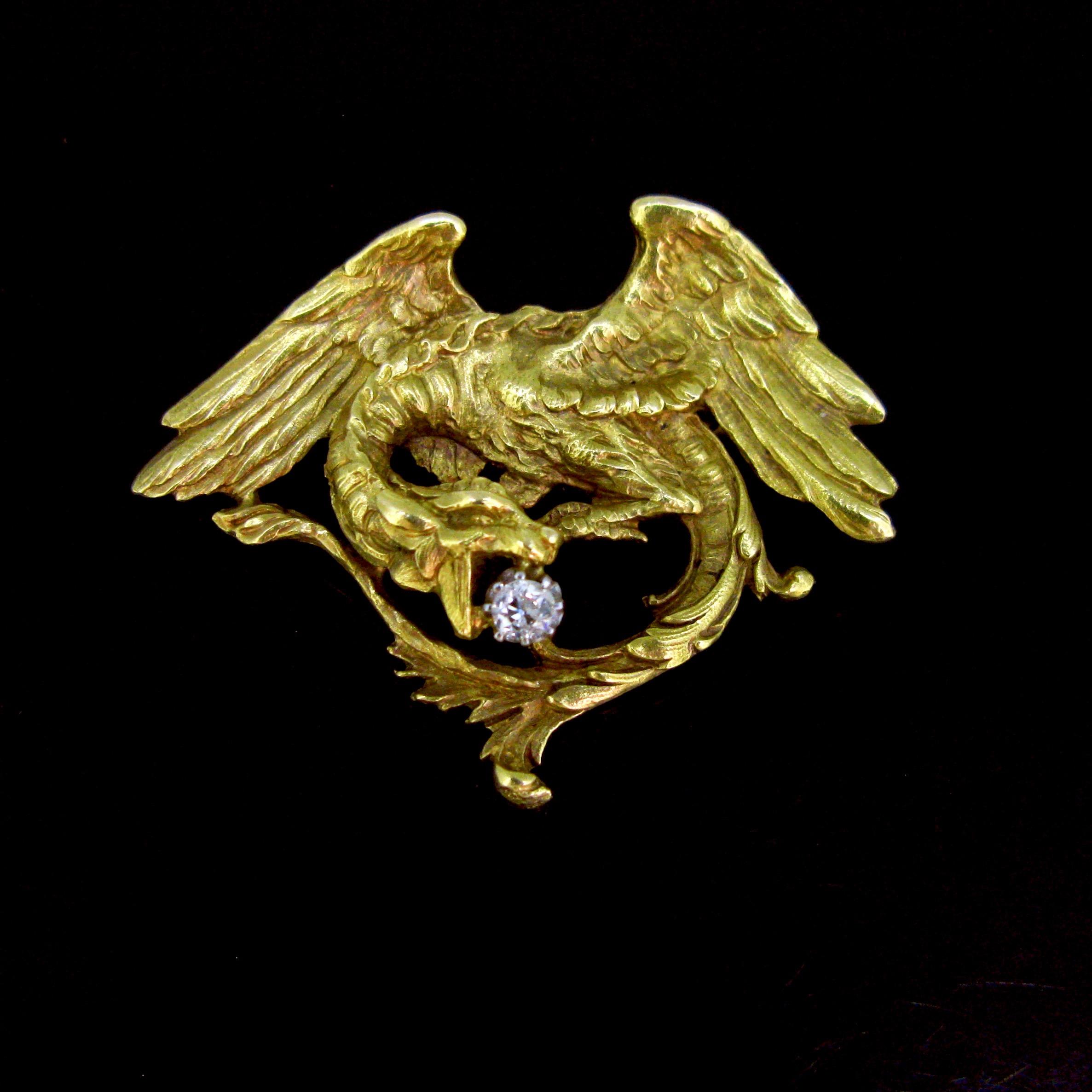 This stunning brooch is from the Art Nouveau era. It features a chimera / griffin holding a diamond in his jaws. The diamond is set on platinum and the brooch is fully made in 18kt solid yellow gold. It has been controlled twice with the French