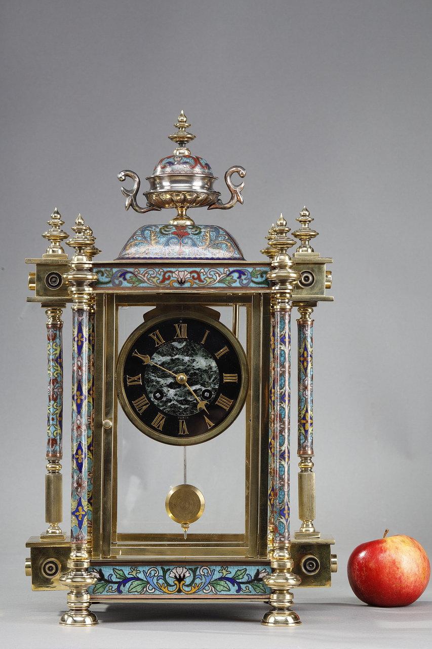Cage clock of the Art Nouveau period in bronze and polychrome cloisonné enamels, of oriental style. The bronze structure is gilded, coppered, and decorated in places with acanthus leaves and flowers. The whole mechanism is surrounded by six columns