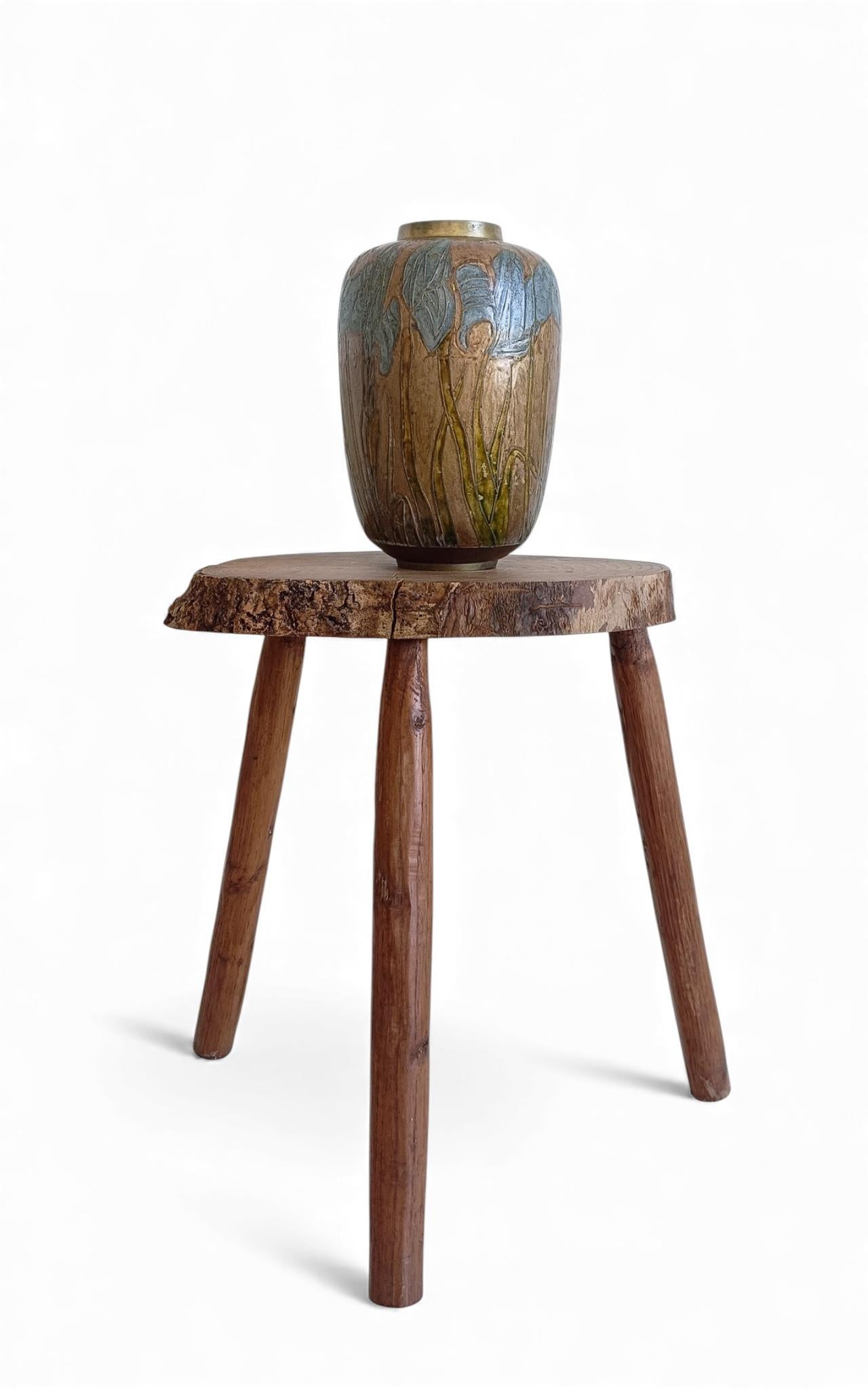 Un grazioso vaso in ottone cloisonné smaltato in stile Art Nouveau, con fiori di iris blu polvere e steli verde chiaro su uno sfondo caldo e arrugginito. Il vaso presenta un delicato mix di colori pastello e polverosi, caratteristici del periodo Art