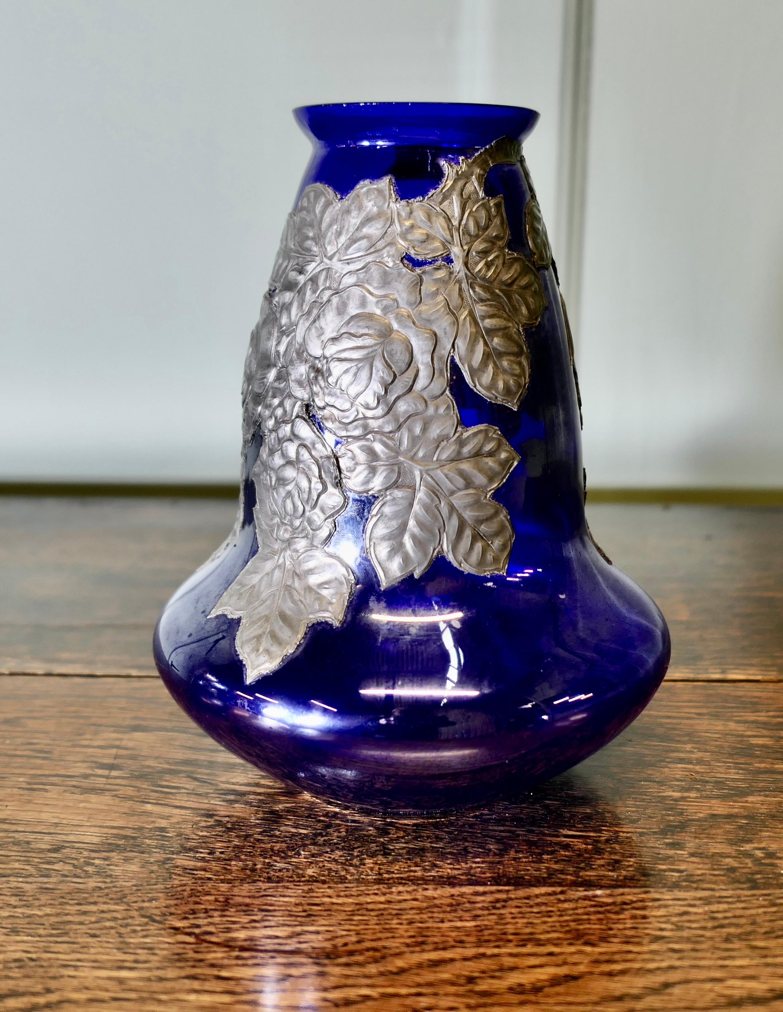 Art Nouveau Cobalt Blue Vase with Pewter Overlay 
Aesthetic cobalt blue glass vase overlayed with pewter in a floral design.  
This is an excellent early 20th Century piece from France, it is 9” tall and 7” in diameter
AW66