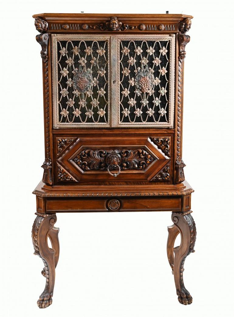 A rare and unusual carved  French walnut cocktail cabinet.
Very unusual piece with carved details and glass 
The back section has hand painted glass crests all surrounded with lead dividers. 
The two doors are polished metal painted with polychrome