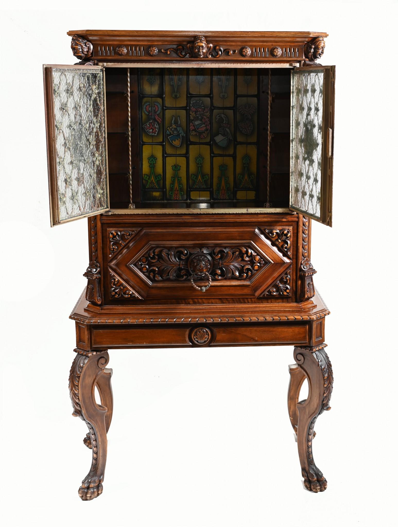 A rare and unusual carved  French walnut cocktail cabinet.
Very unusual piece with carved details and glass 
The back section has hand painted glass crests all surrounded with lead dividers. 
The two doors are polished metal painted with polychrome