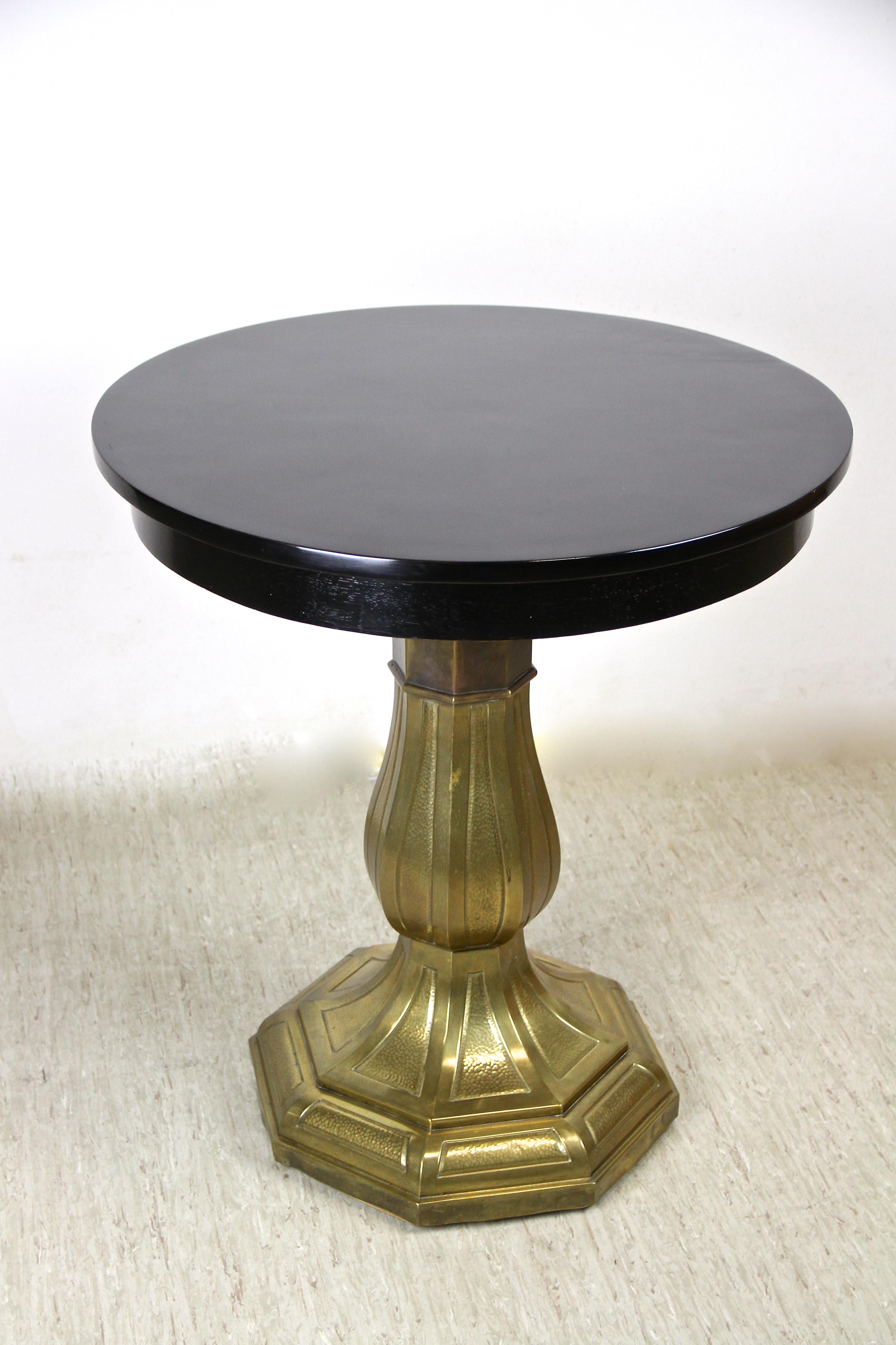 Bemerkenswerter schwarz lackierter Jugendstil Couchtisch aus Wien/ Österreich aus der Zeit um 1910. Die runde, glänzende Tischplatte sitzt auf einer kunstvoll geformten Säule mit achteckigem Sockel. Das messing-/kupferbeschichtete Meisterstück