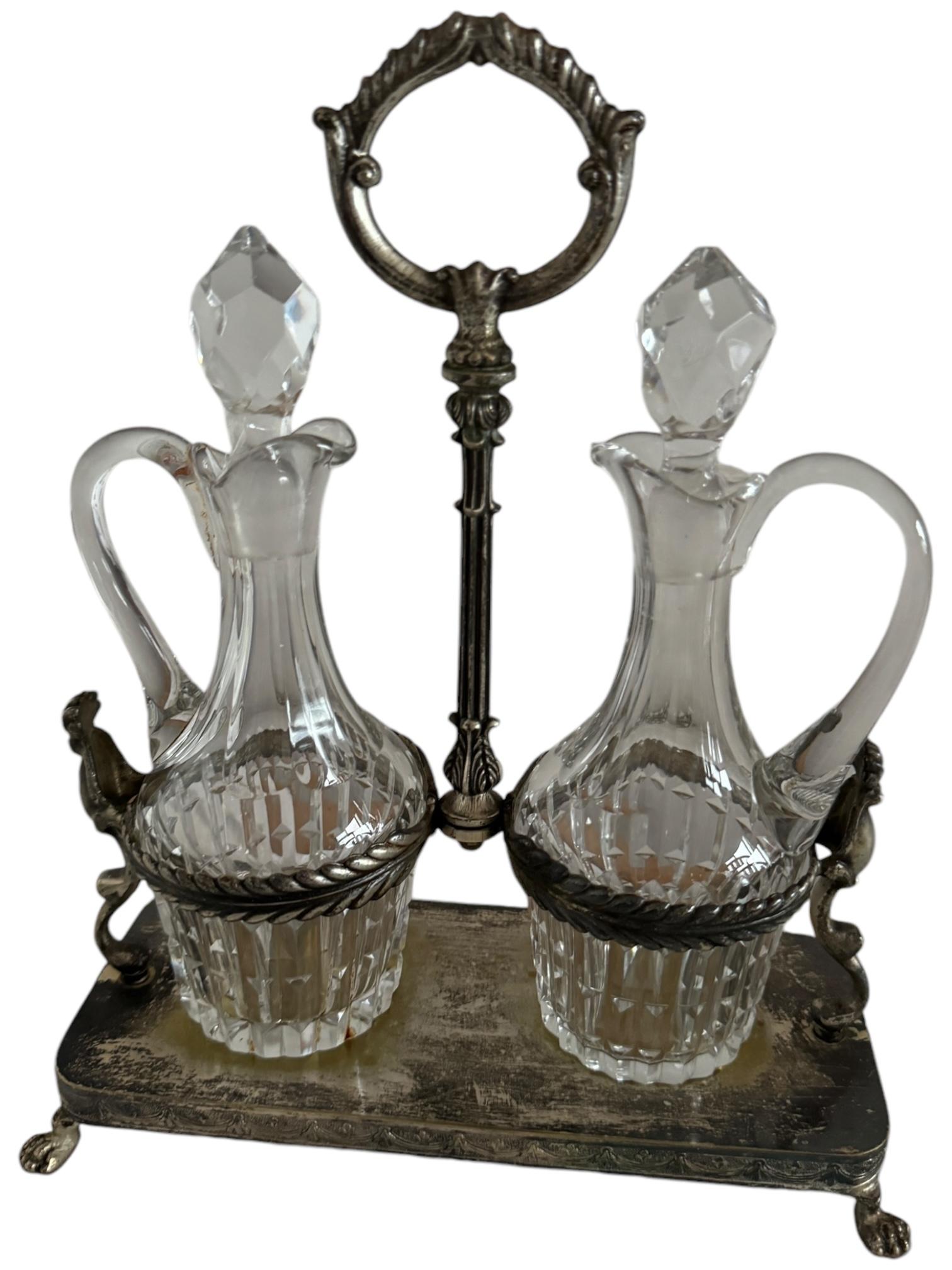Continental silver plated cruet, most likely English or Italian and dating to the early 20th century. Exquisitely crafted and with an engraved rim around the base, standing on 4 animal shaped feet, with 2 glass bottles with stoppers. The holder is
