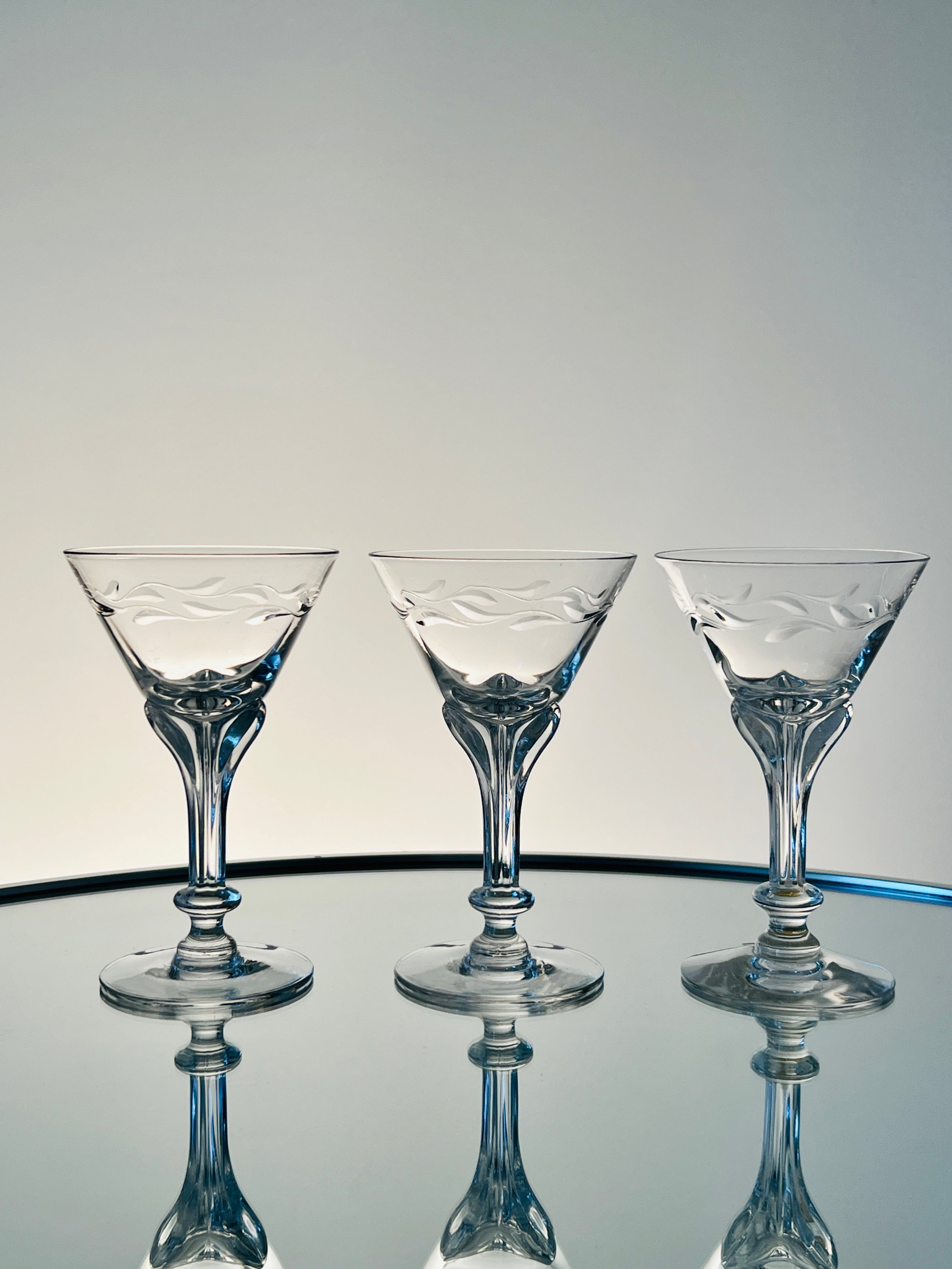 Set / 12 crystal cocktail glasses from the Lenox Wreath Collection by Tiffin. The handblown stemware feature an elegant engraved wreath motif and a stylized floral stem, invoking elements of both Art Nouveau and Art Deco designs. Can be used as