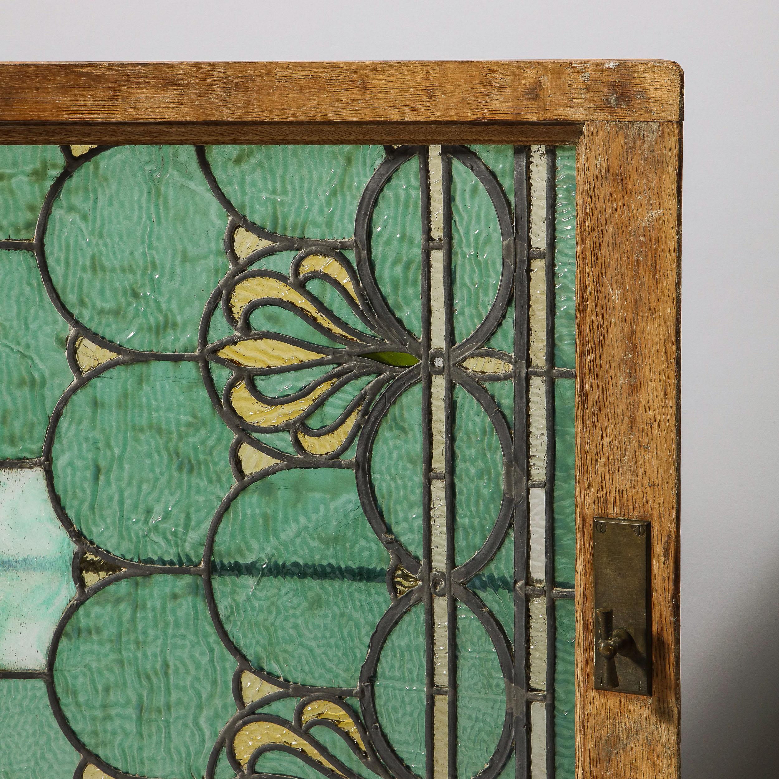This stunning Art Nouveau window/ panel was realized in the United States in 1907, attributed to Tiffany & Co. The piece features a mosaic of interlocking demilune arch forms in hues of mottled textural seafoam and emerald with citrine accents, all
