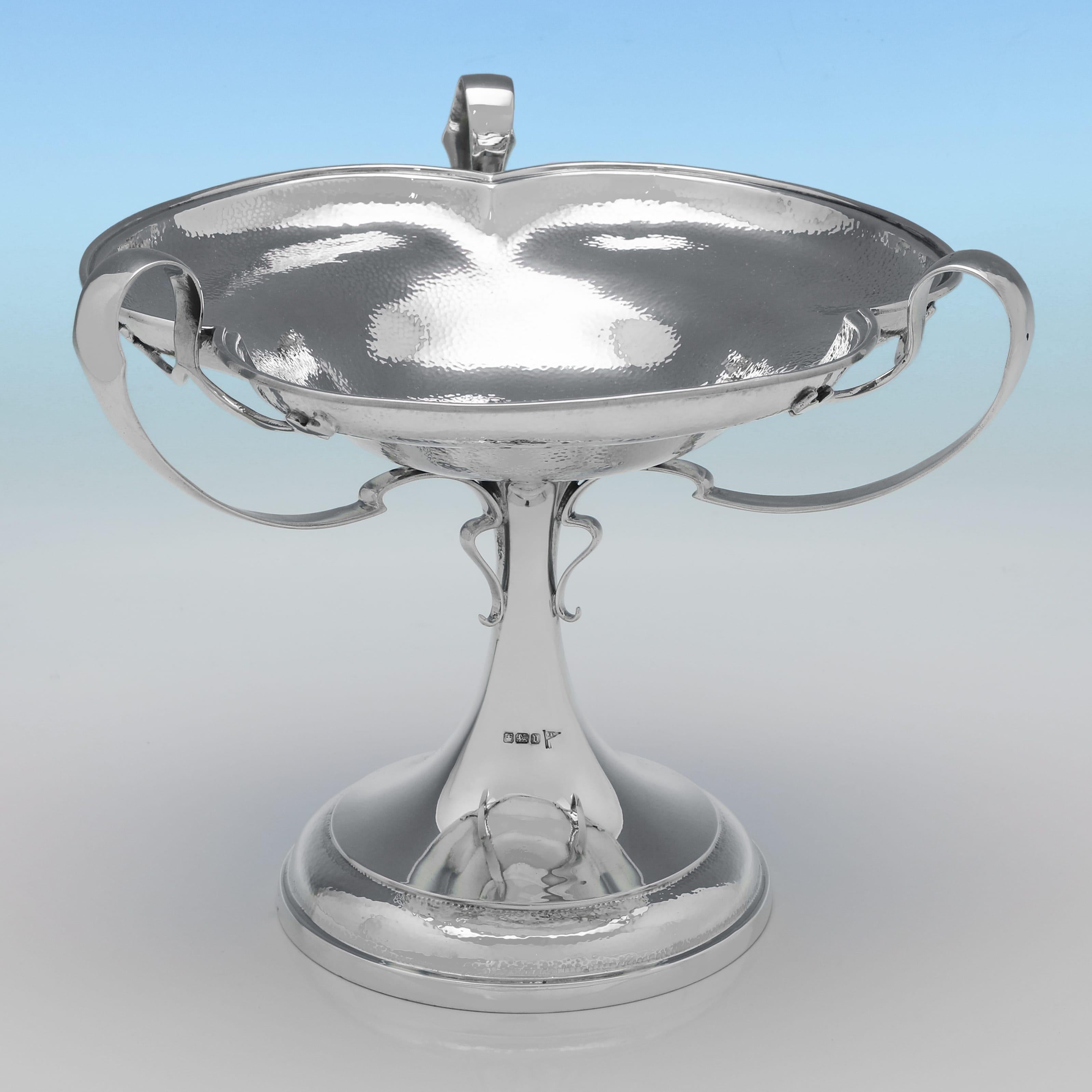 Marchiata a Sheffield nel 1913 da Walker & Hall, questa attraente tazza in argento sterling di epoca George V. è di gusto art nouveau, con finitura piallata e 3 manici. La tazza misura 22 cm di altezza, 26 cm di diametro e pesa 29,37 once troy.