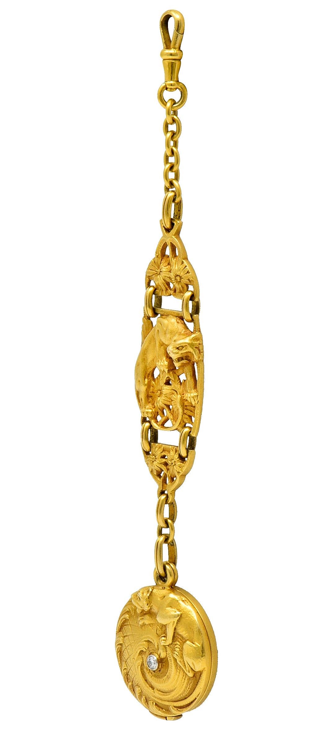 Long antique watch chain terminates as a circular locket; back is inscribed with monogram

It swivels open to reveal a plastic covered recess

Locket is highly rendered to depict a jaguar climbing scrolled foliate whiplash

Centering a bezel set