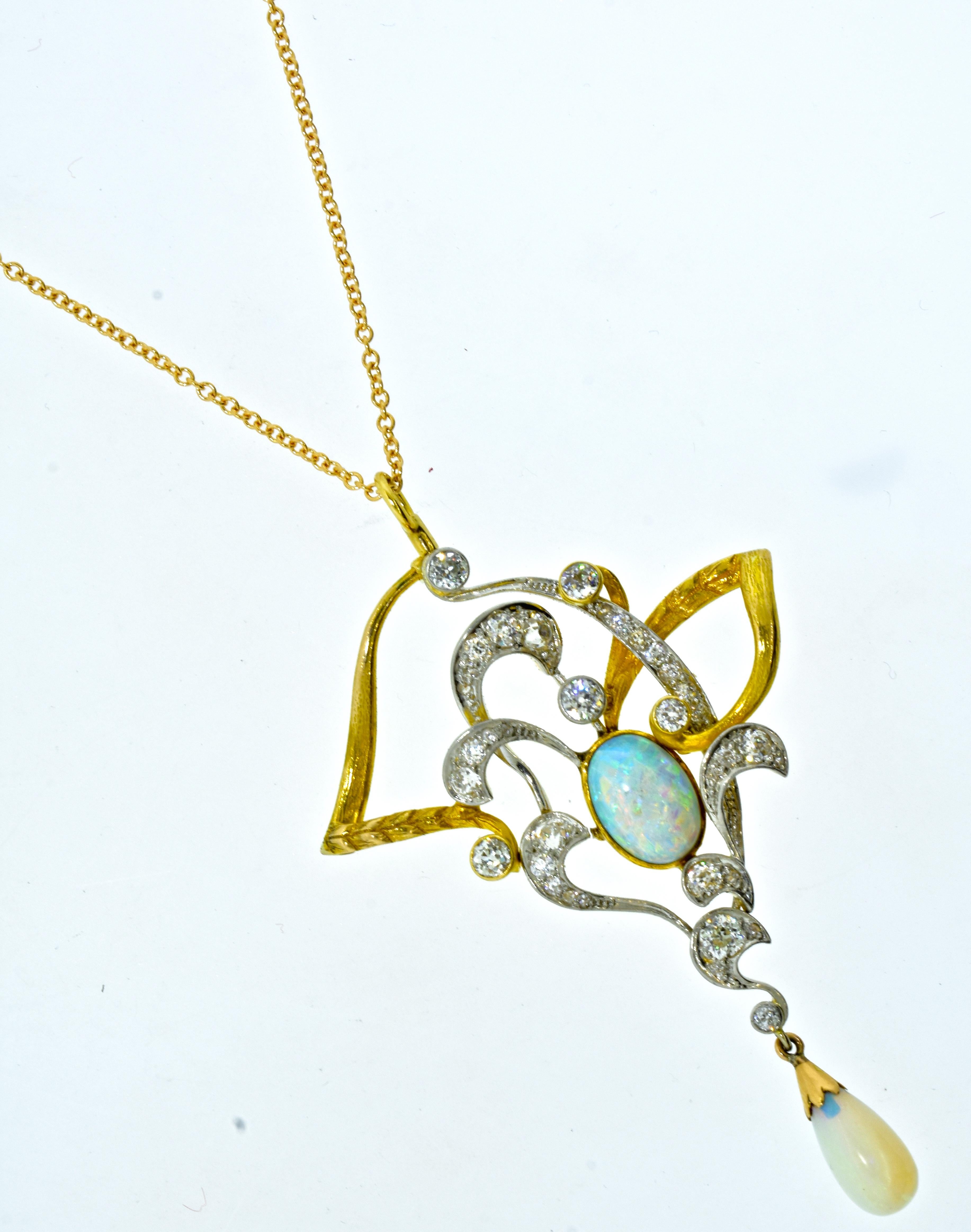 Art Nouveau pendant in platinum and yellow gold.  The asymmetrical pendant is 2.5 inches long, centering a blue, green and red opal measuring 11.0 mm. by 7.5 mm. by 4.0 mm., approximately. is accented with 35 European cut diamonds weighing an