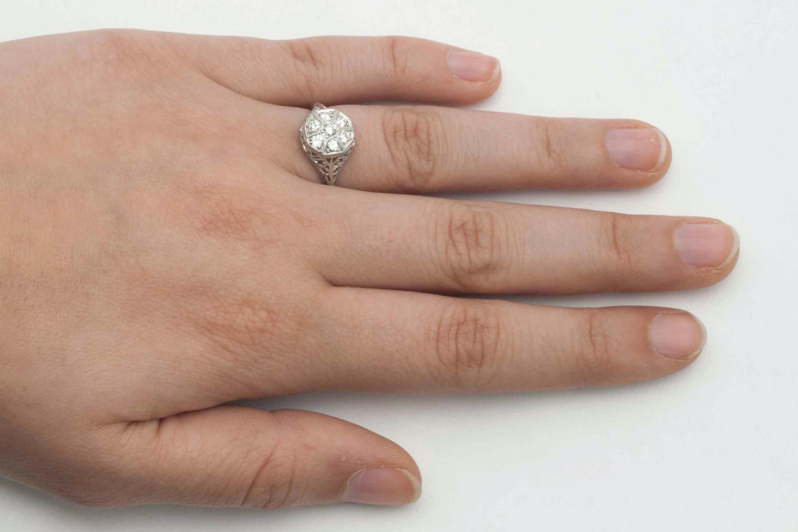 The Minneapolis vintage engagement ring. Seven matched old mine cut diamonds are set in a cluster that give the appearance of a large solitaire. The graceful filigree shoulders taper to a fine, knife edge band for a dainty feel. The work on the