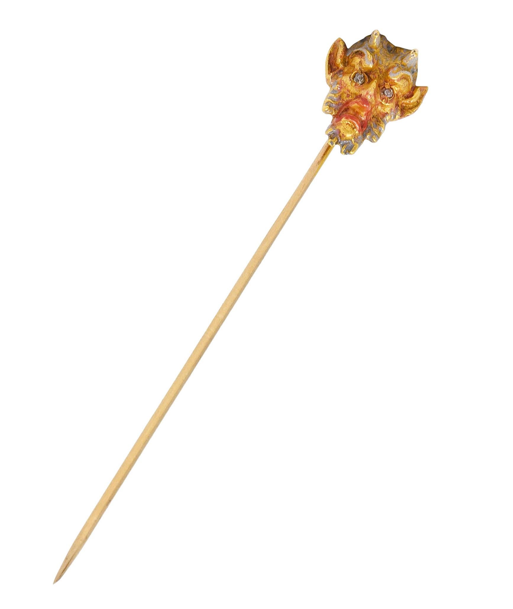 Stickpin designed as a highly stylized head of a satyr 

With textured hair, agape mouth, and enamel glossed horns 

Enamel is translucent red and gray - exhibiting some loss 

Accented by diamond eyes

Tested as 18 karat gold 

Circa: 1905

Satyr