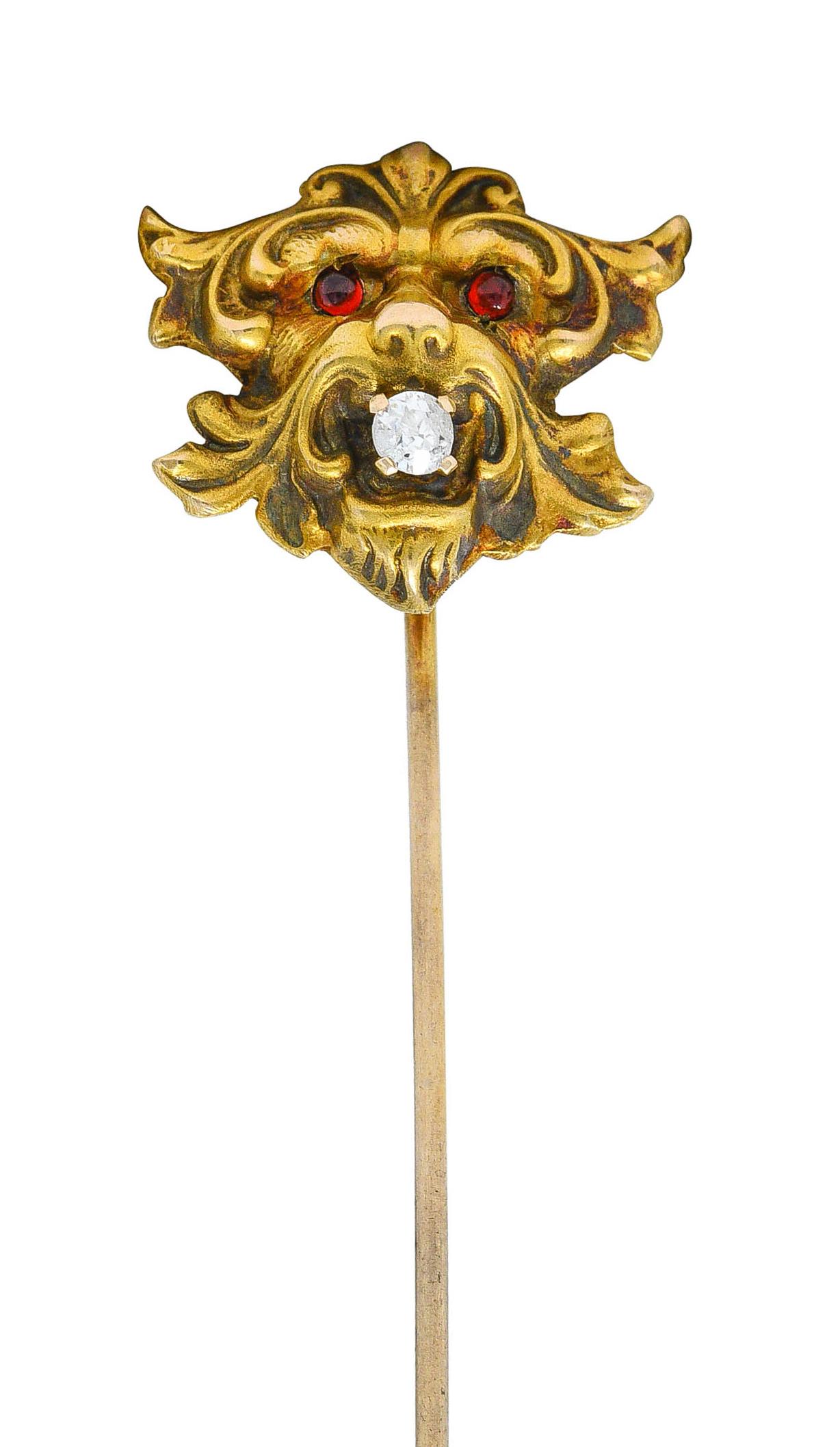 Depicting a stylized whiplash lion

With bright red garnet cabochon eyes

And an old European cut diamond clutched in its jaw

Eye clean and white while weighing approximately 0.05 carat

Lion tested as 14 karat gold while pin stem is stamped for 10