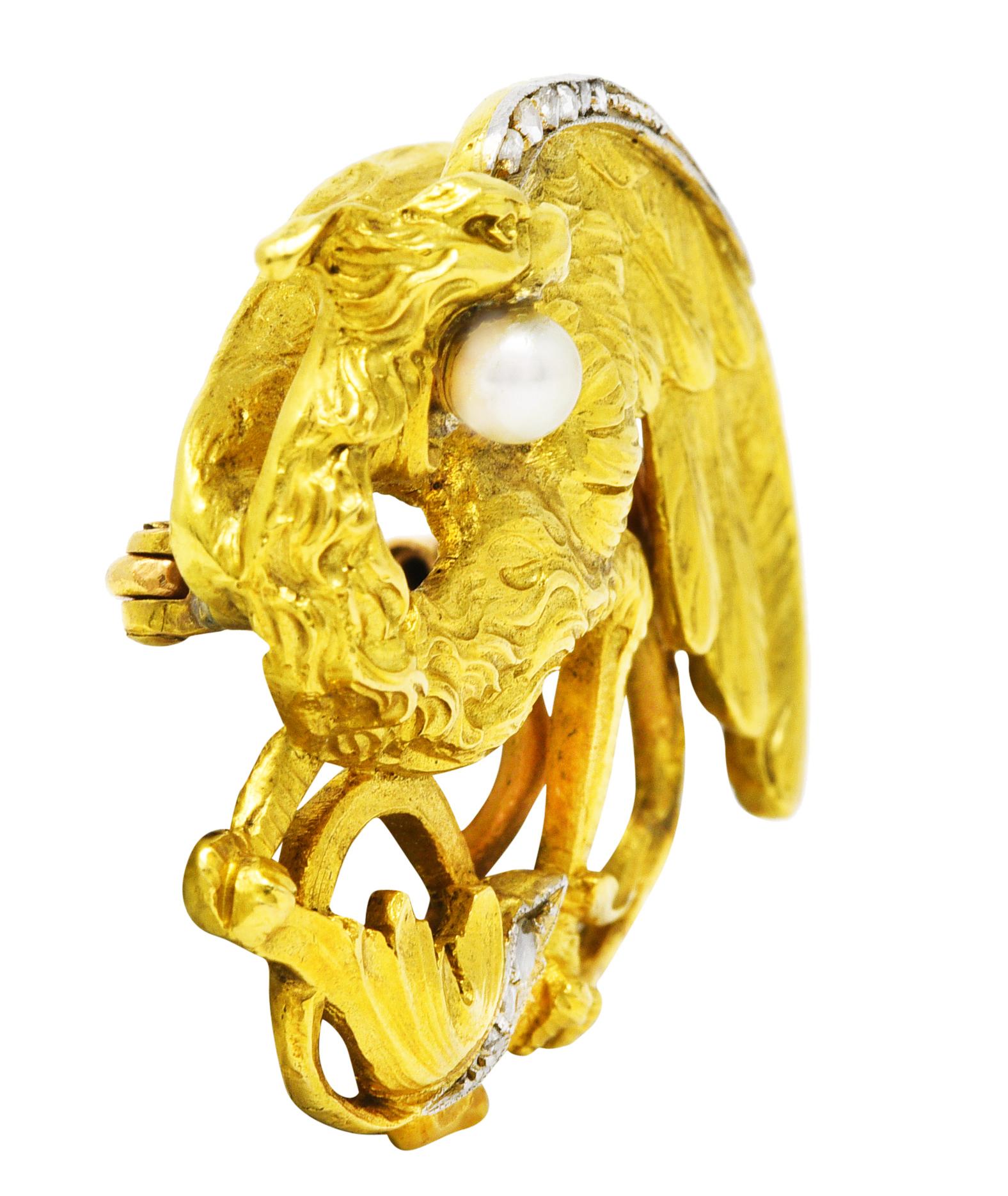 Brooch is designed as a winged griffin with texturous flowing fur, sweeping feathers, and a curling tail. Clutching a 3.5 mm round pearl in its beak - white in body color with iridescence and good luster. Accented by rose cut diamonds flush set in