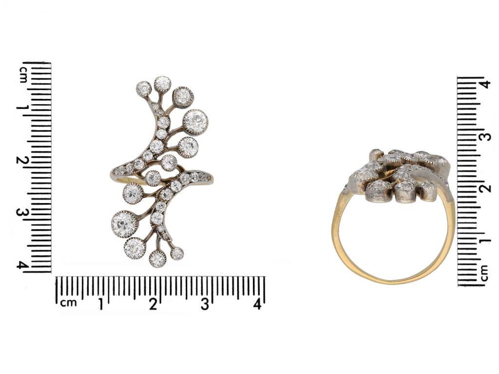 Art Nouveau diamond ring. Set with a total of thirty two round old cut diamonds of varying sizes in open back grain and millegrain settings with an approximate combined weight of 3.00 carats, to an impressive sprayed cross over form with intricate