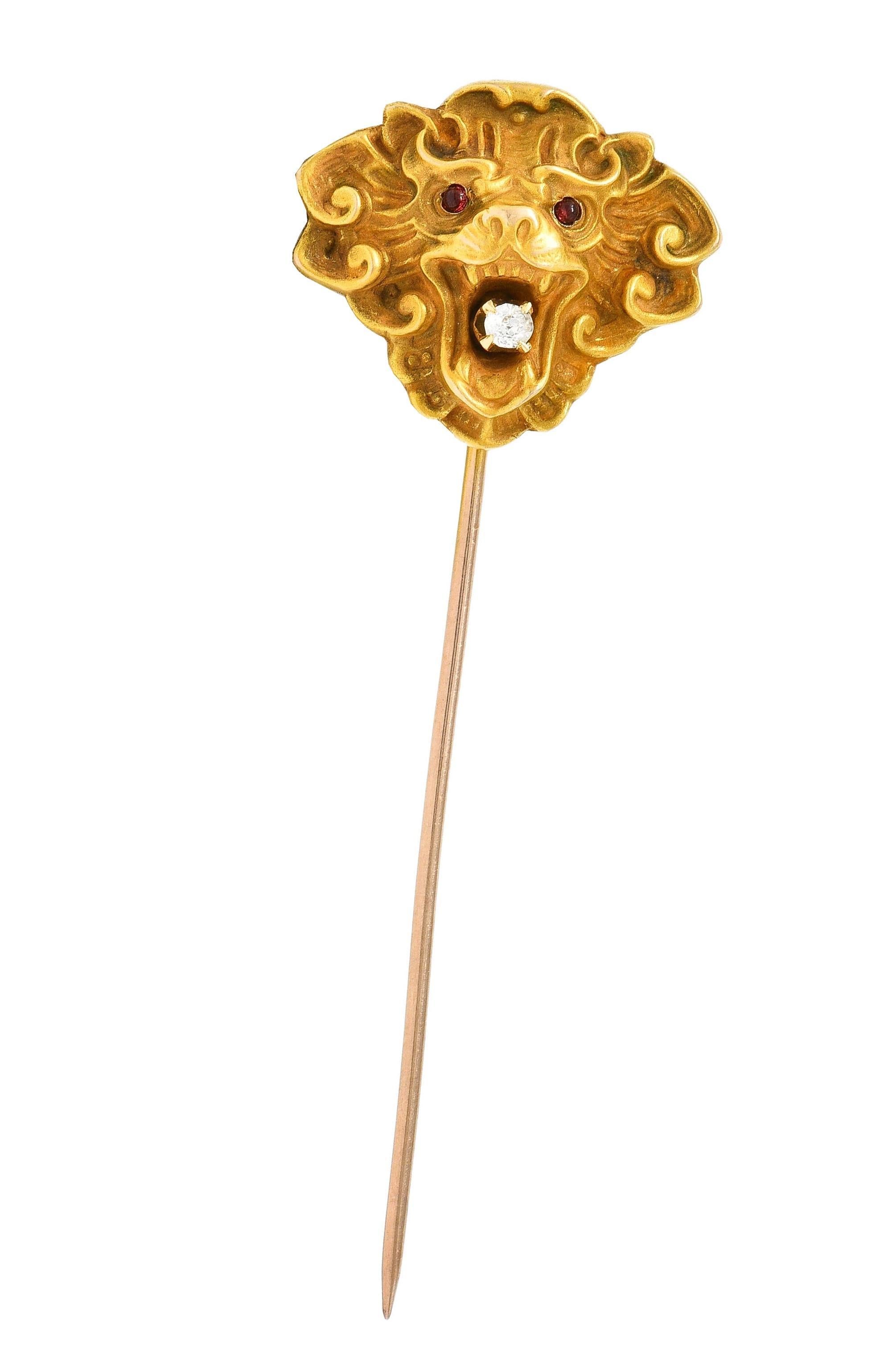 Designed as a highly rendered lion head with grooved detail
Depicted with furrowed brow and scrolling mane
Accented by 1.5 mm round tourmaline cabochons
Flush set as eyes and transparent pinkish-red
Clutching an old mine cut diamond in its