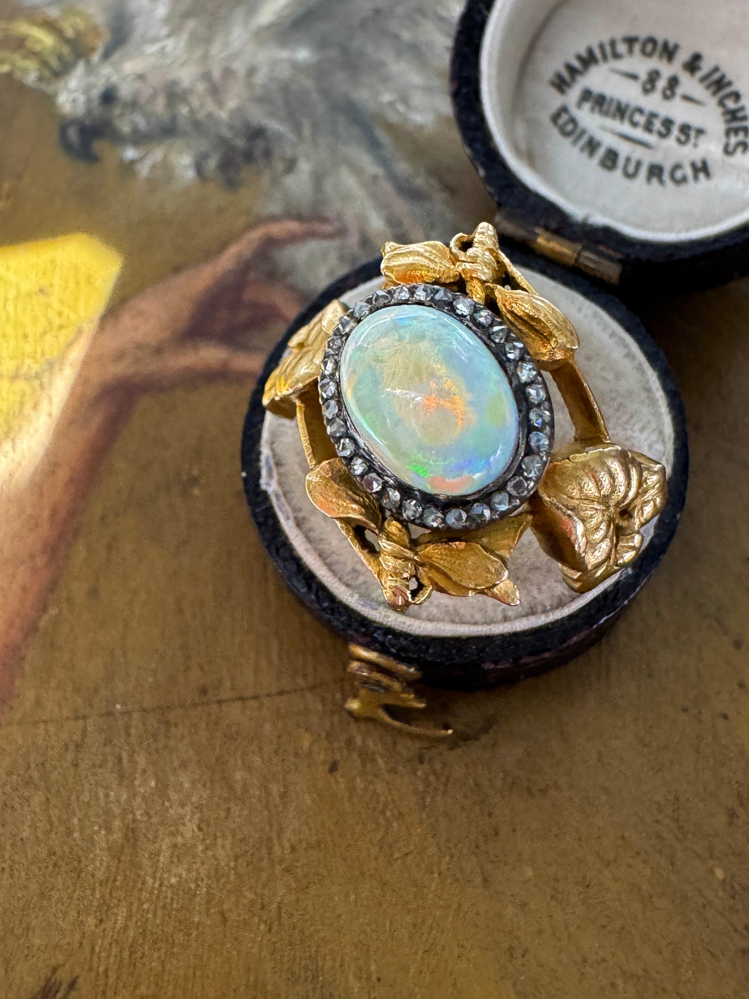 Crafted during the height of the Art Nouveau era, this ultra charming and rare ring is a celebration of natures beauty and artistic excellence. At its heart lies a luminous cabochon opal, glowing with a mesmerizing kaleidoscope of shifting colors,