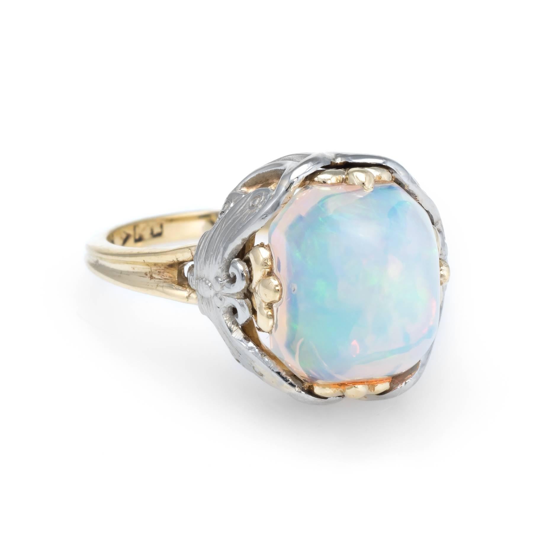 Finely detailed vintage Art Nouveau era ring (circa 1900s to 1910s), crafted in 14 karat yellow & white gold. 

Centrally mounted high dome natural opal measures 9.5mm x 8mm (estimated at 6 carats). The opal is in excellent condition and free of