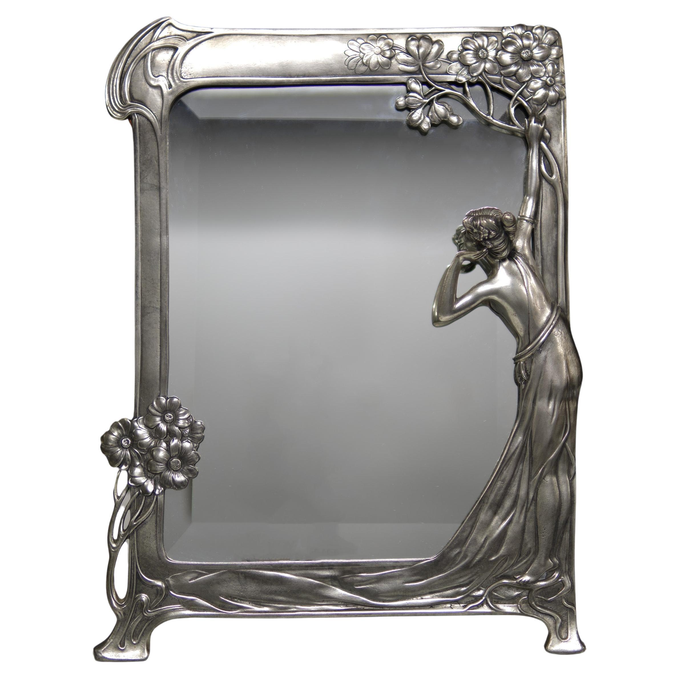 Magnifique  Miroir biseauté Jugenstill de la Royal Dutch Pewter Company. Une femme élégante qui se regarde dans le miroir. Le miroir est en très bon état et constitue un exemple exceptionnel.  Vers 1920 .  signé au dos Le cadre représente une dame