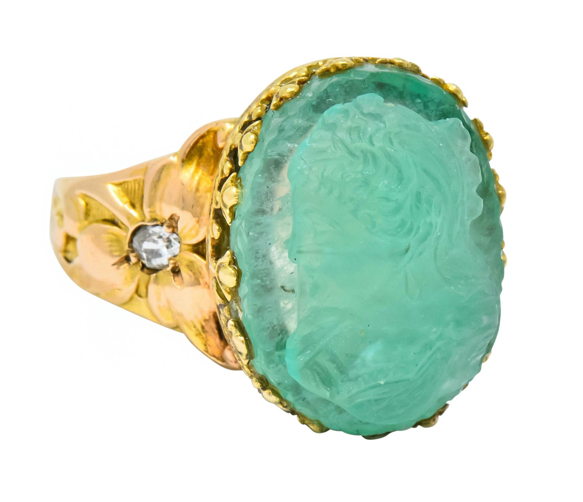 Centering a deeply carved emerald cameo, translucent and sea foam green, depicting a profile of an elegantly dressed woman

Claw set with stylized foliate motif prongs and flanked by two old mine cut diamonds weighing approximately 0.16 carat total,