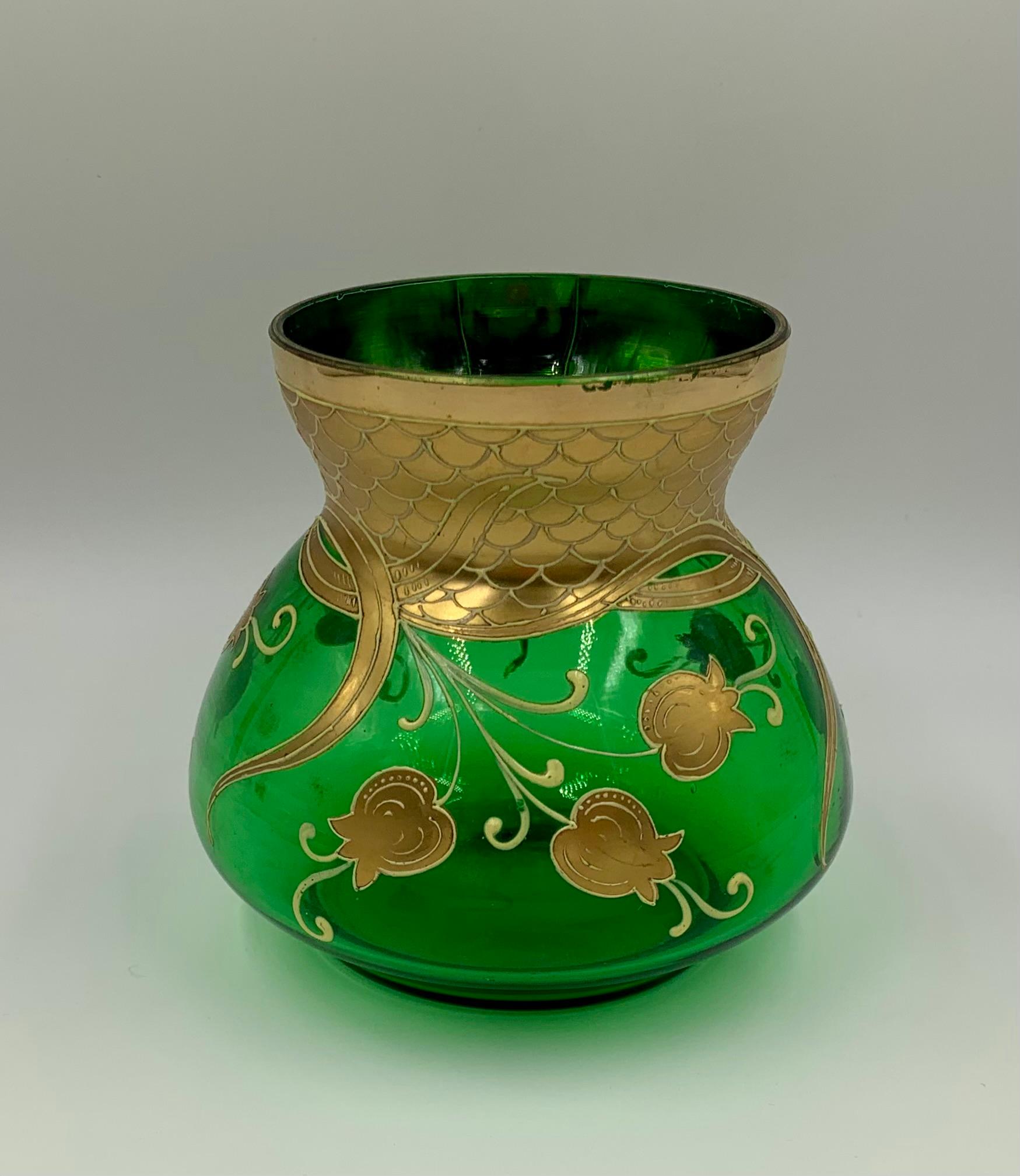 Jugendstilvase aus smaragdgrünem Kunstglas mit vergoldetem und weißem Emaildekor, das stilisierte Maiglöckchen, kunstvoll gerollte Blätter und goldene Schuppen darstellt
Anfang des 20. Jahrhunderts
Oberteil und Hals reich verziert mit goldenen