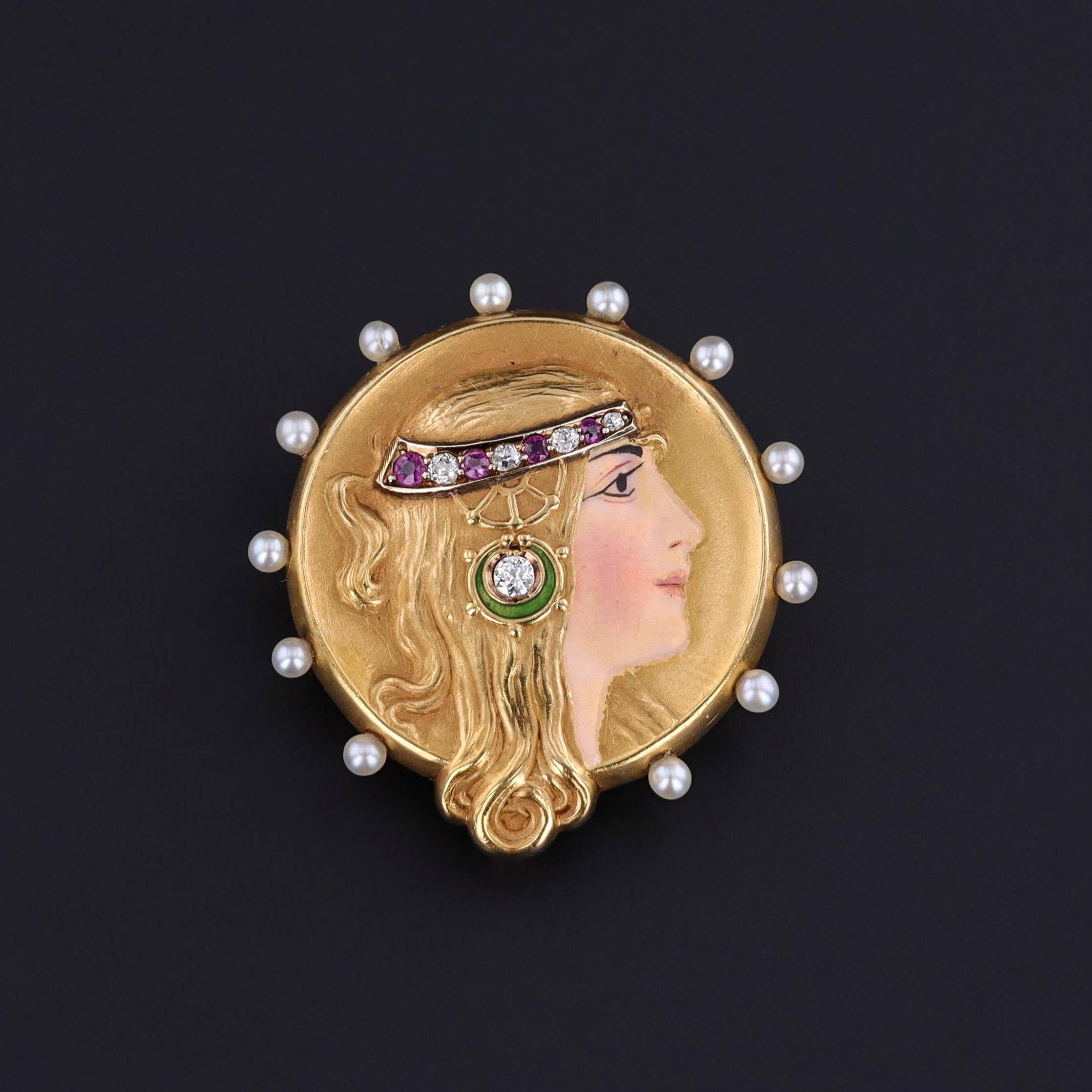 Un'antica spilla di epoca Art Nouveau con una donna in oro 14k e smalto con perle, diamanti e rubini. Risale al 1900 e viene fornito nella sua scatola di gioielli originale.

Il pezzo misura 1,15 pollici per 1,1 pollici di larghezza e pesa 5,65