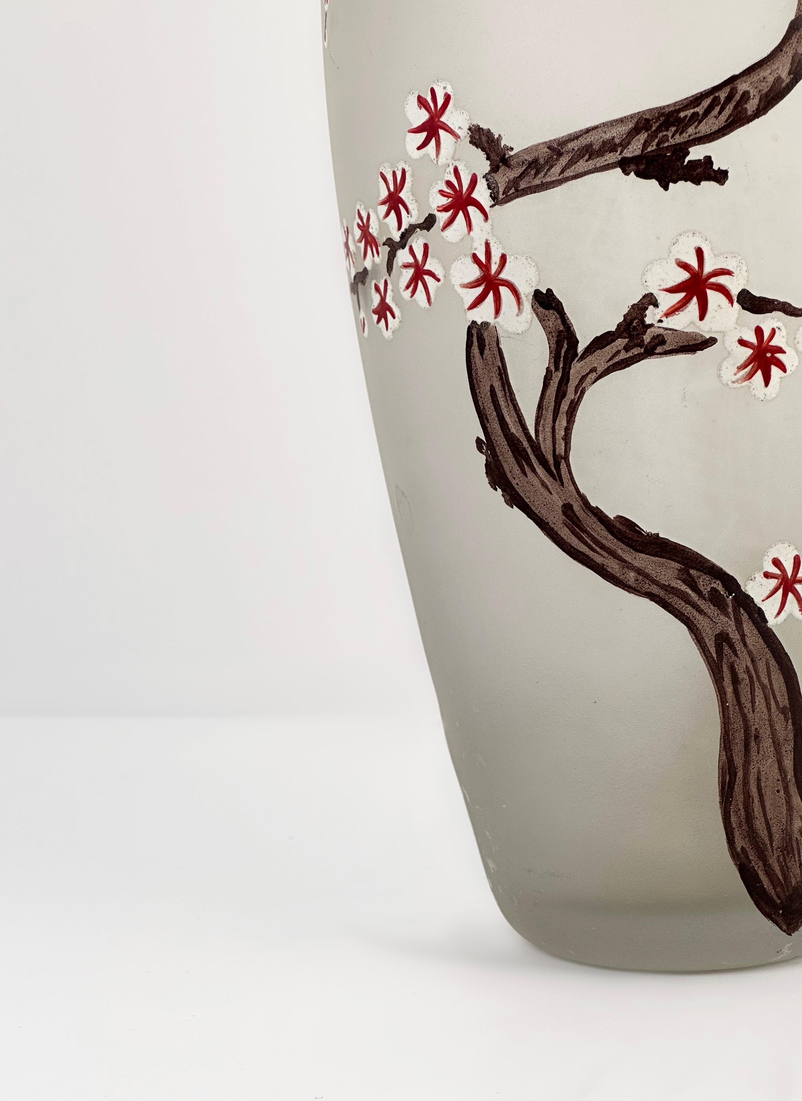 An elegant Art Nouveau frosted glass vase, a simple masterpiece. This exquisite piece is adorned with a delicate hand-enameled cherry blossom motif on the front, complemented by a striking red border on the lip. Though unsigned, its unparalleled